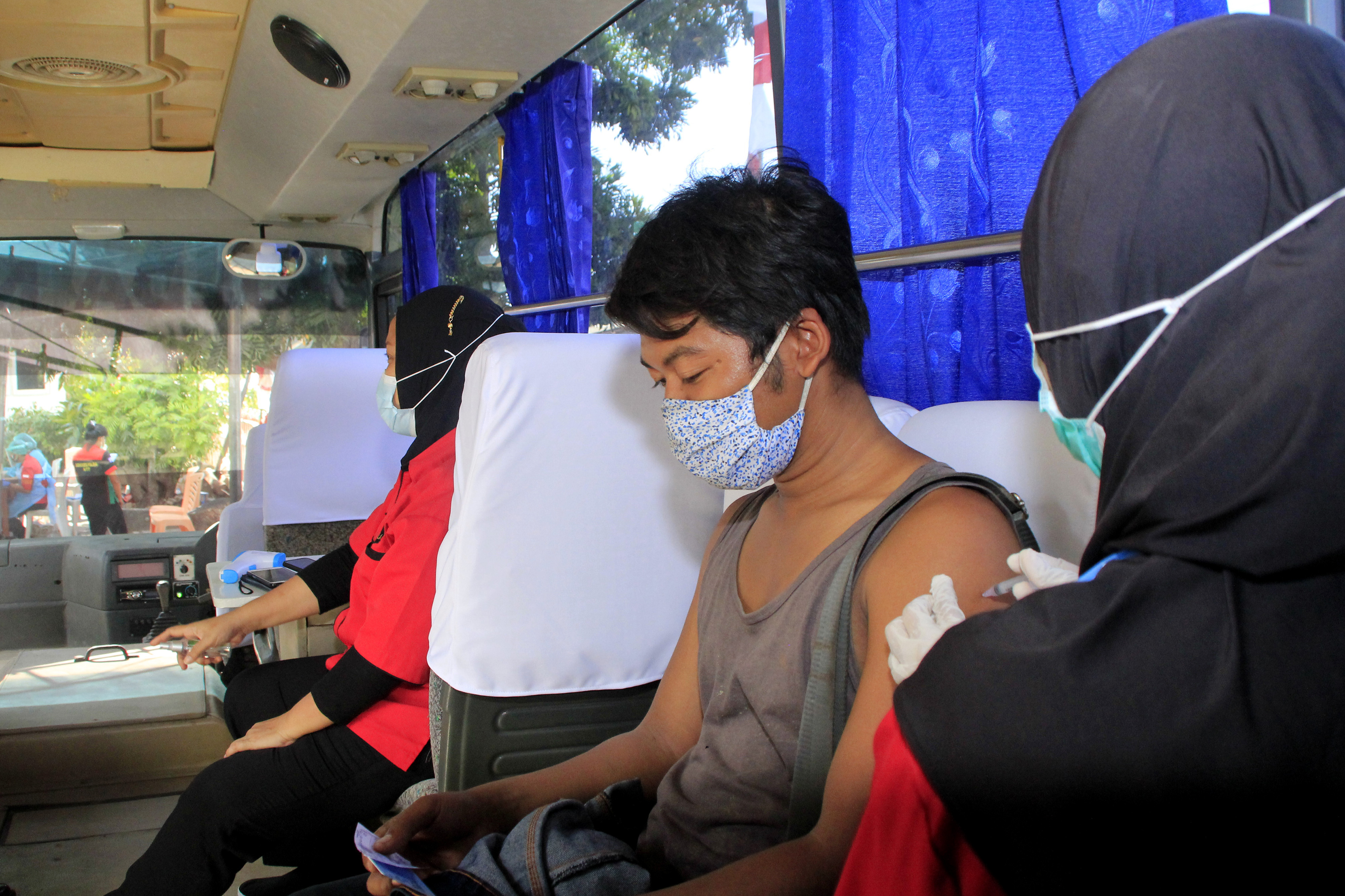 Warga menerima suntikan vaksin covid-19 di atas bus yang didesain khusus untuk pelaksanaan vaksinasi covid-19 di Kota Kupang, NTT.