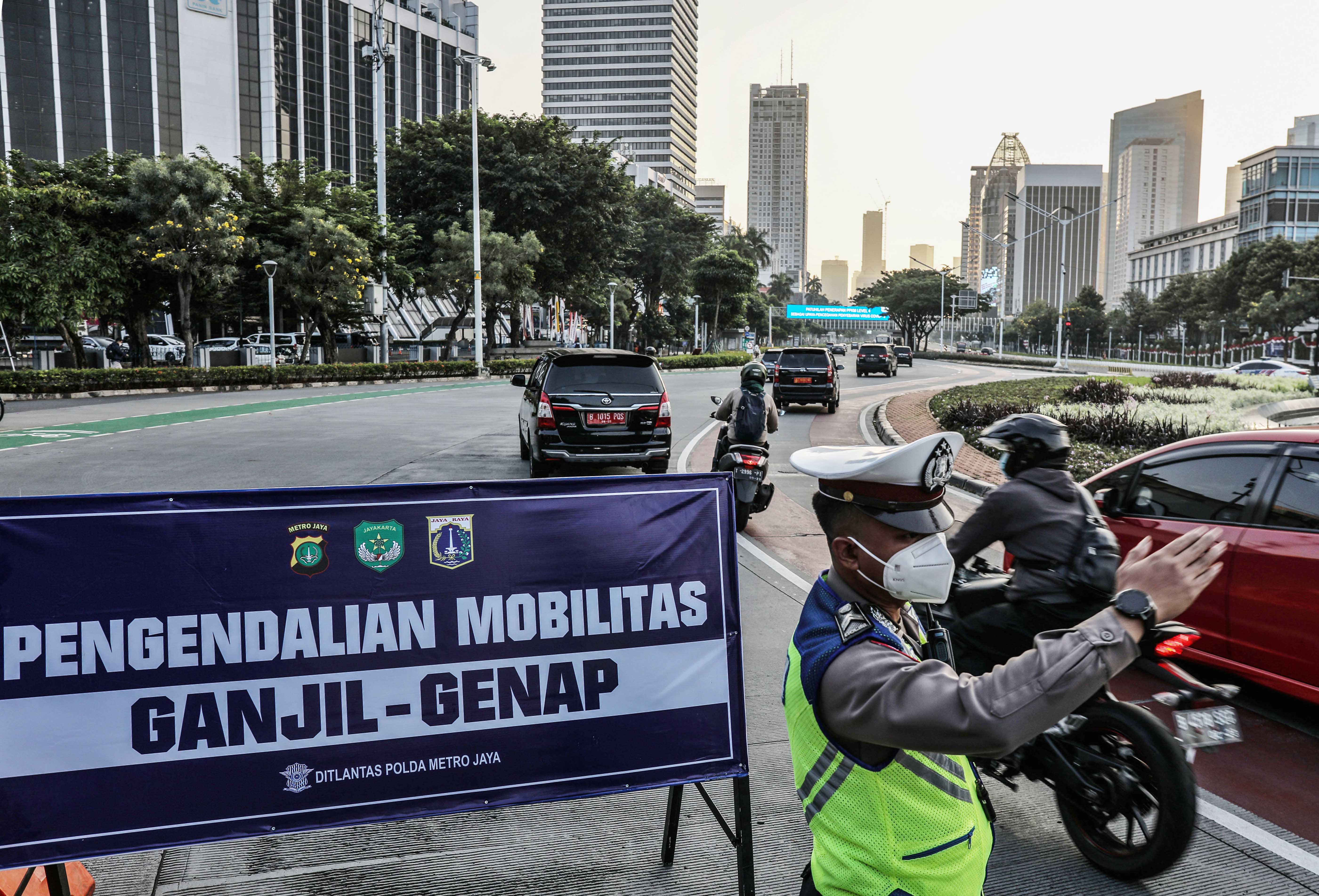 Petugas kepolisian mengalihkan kendaraan berplat nomor ganjil saat pelaksanaan pengendalian mobilitas ganjil genap.