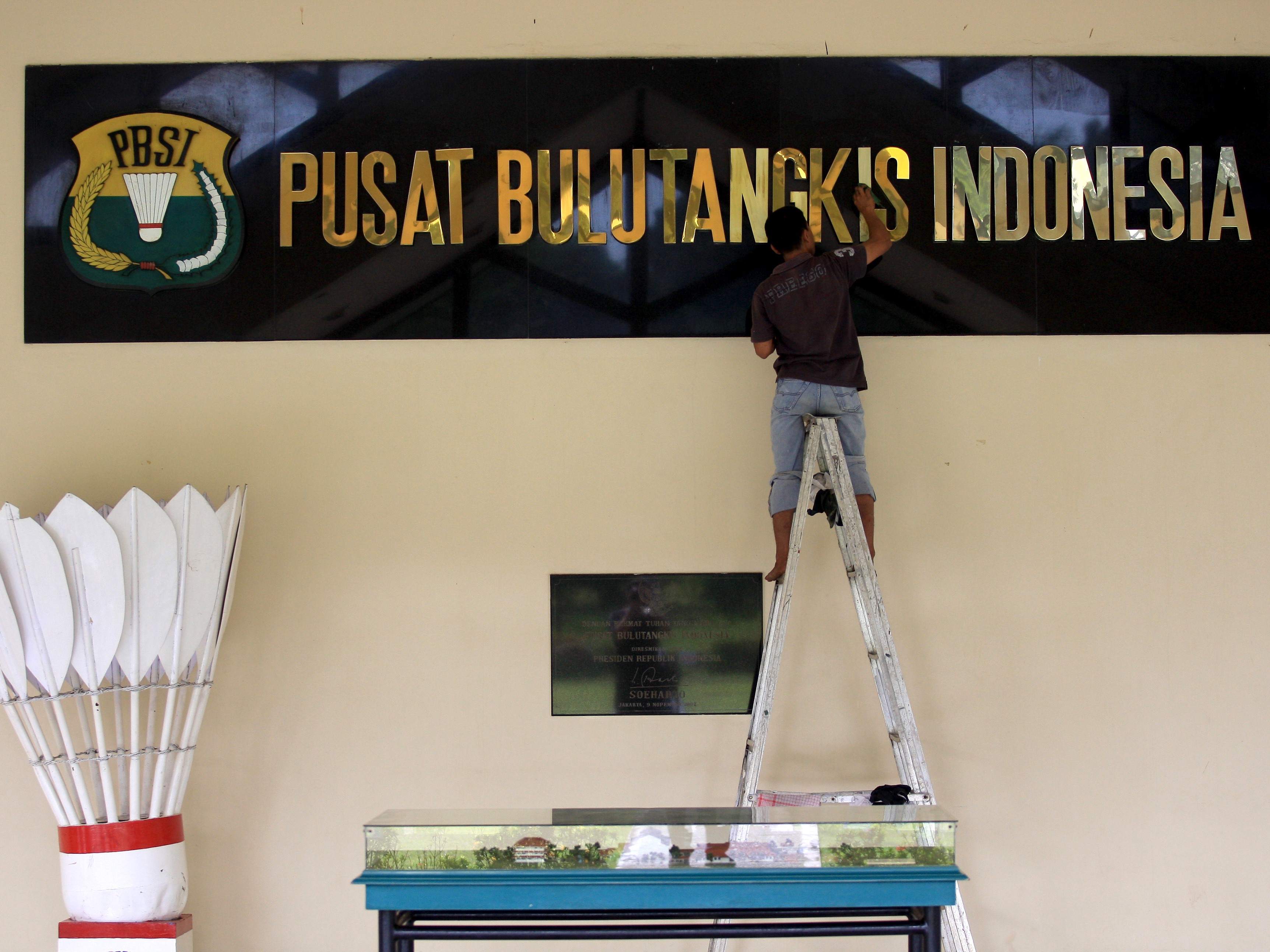 Seorang petugas sedang membersihkan papan nama di Pelatnas Persatuan Bulu Tangkis Seluruh Indonesia (PBSI) di Cijantung, Jakarta.