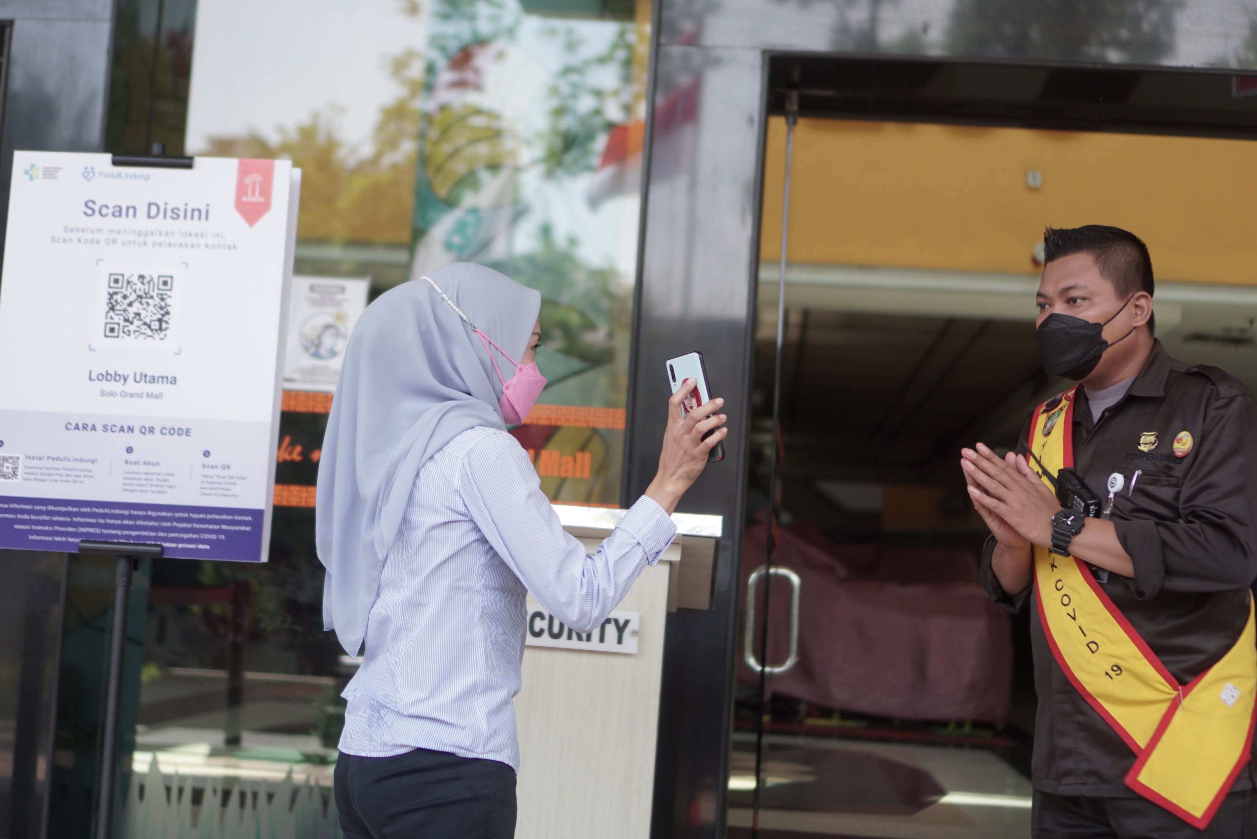 Pengunjung menunjukkan kepada petugas keamanan hasil pemindaian kode batang melalui aplikasi PeduliLindungi saat akan memasuki pusat perbela