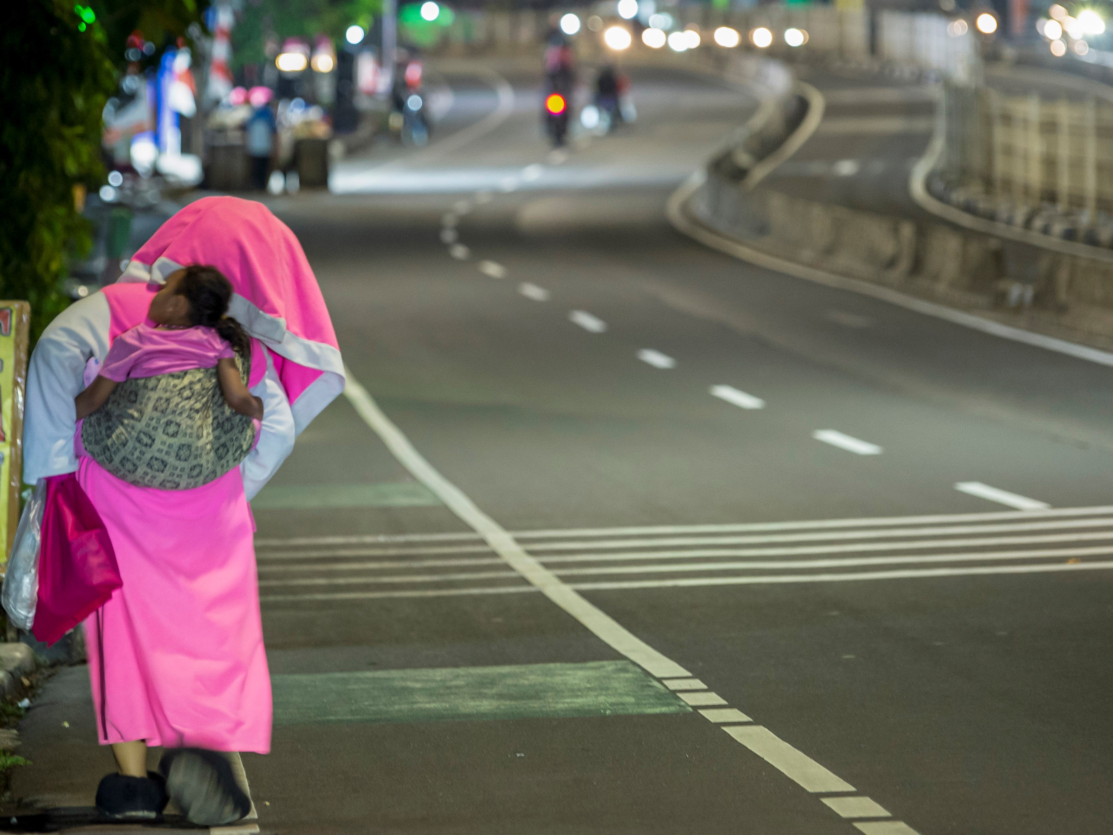 Seorang pengamen berkostum badut menggendong anaknya saat berjalan di kawasan Mampang, Jakarta, Kamis (12/8).