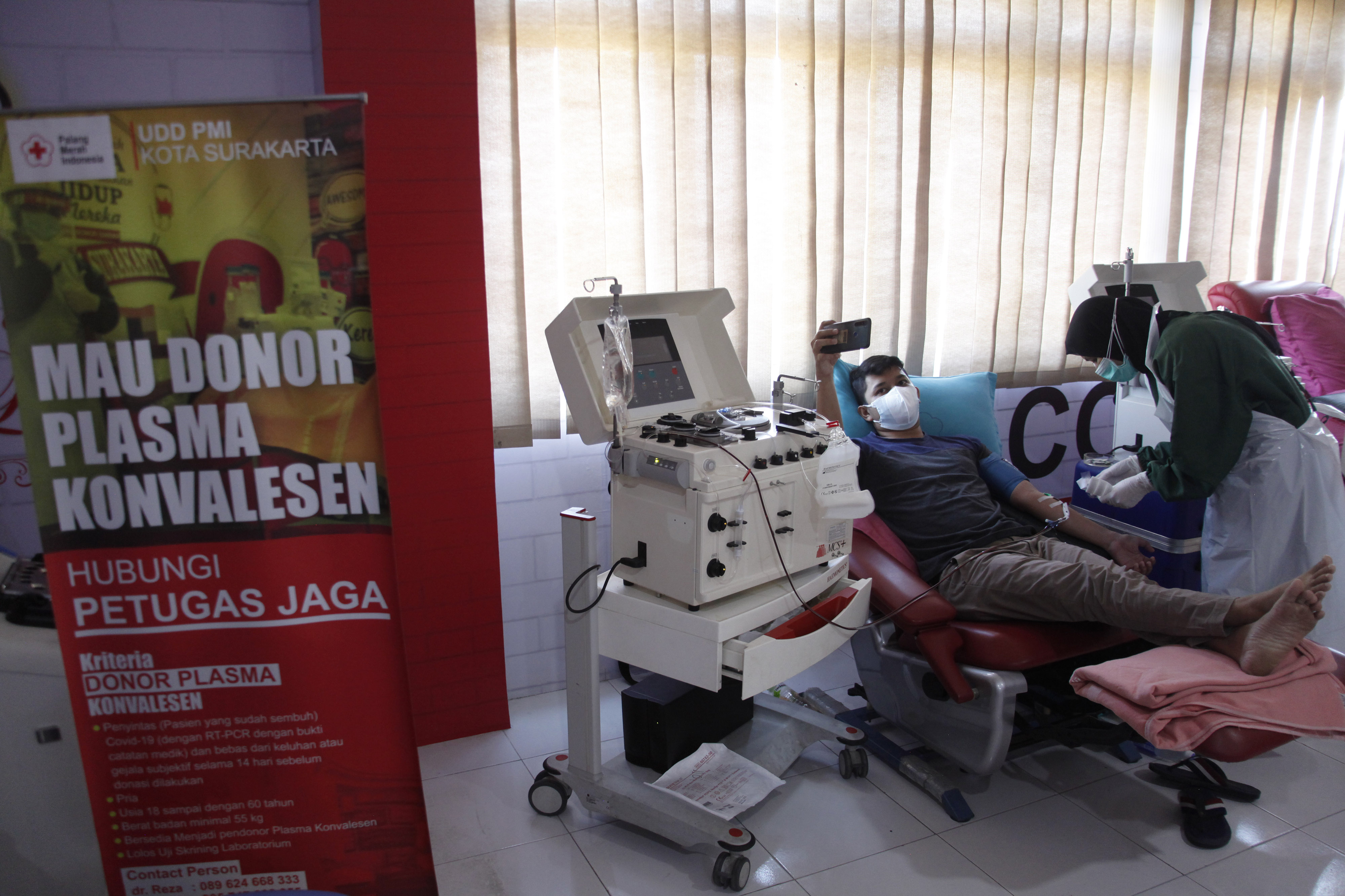 Warga penyintas covid-19 berswafoto saat mendonorkan plasma konvalesen di Palang Merah Indonesia (PMI) Solo, Jawa Tengah.