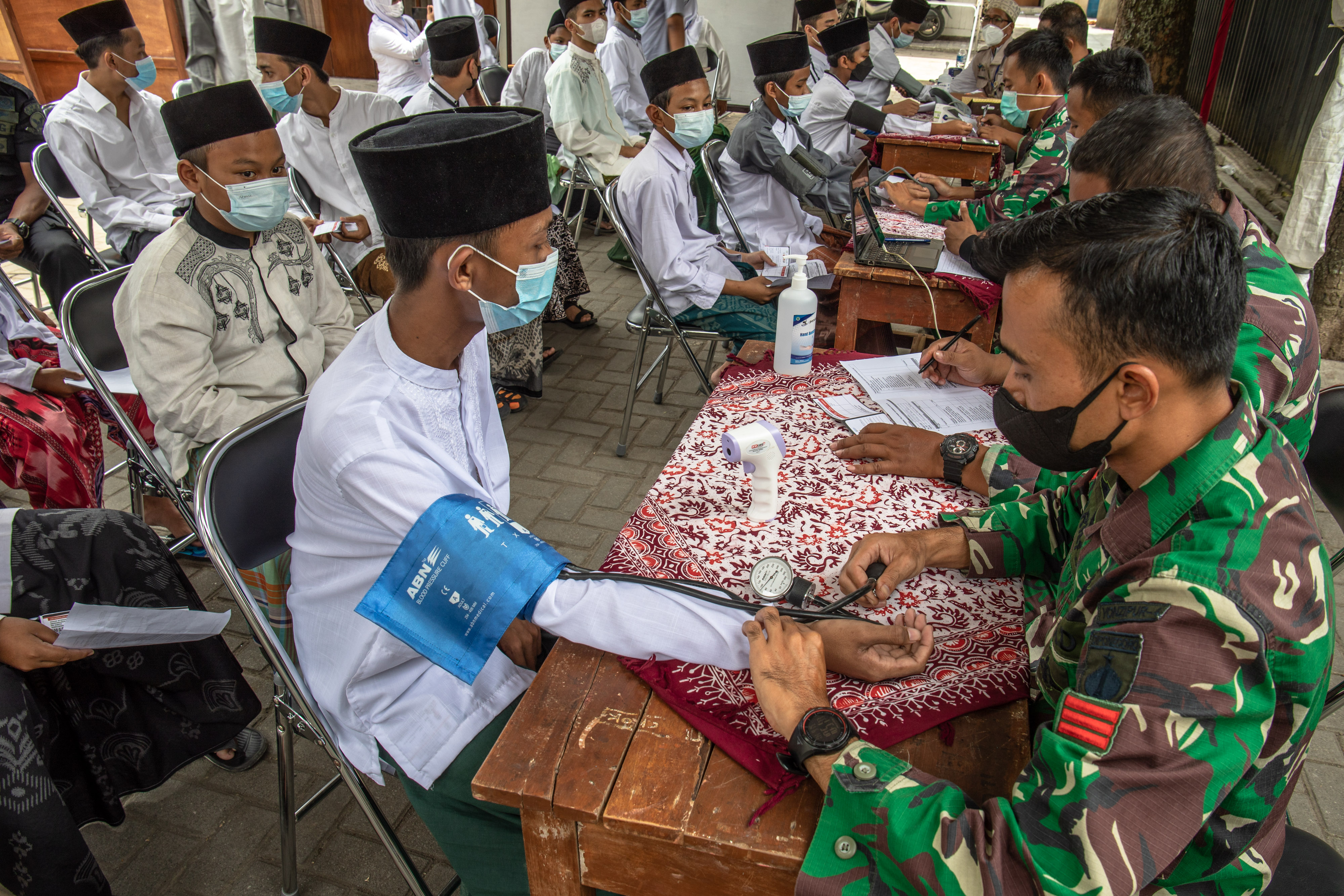 Prajurit Kesehatan TNI saat memeriksa tekanan darah santri sebelum divaksin covid-19.