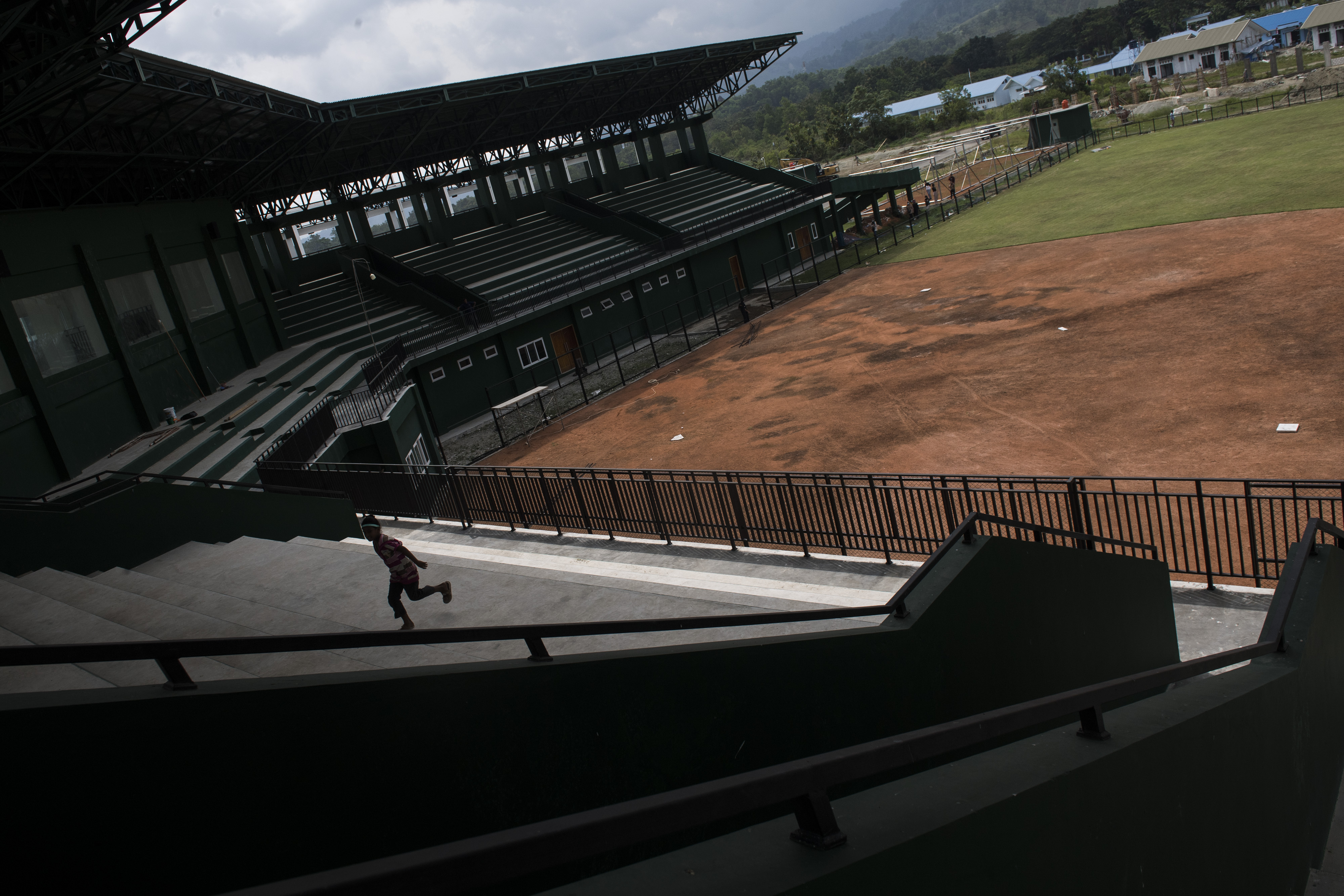 Seorang warga berlari di area tribun penonton lapangan softball wilayah Jayapura, Papua.