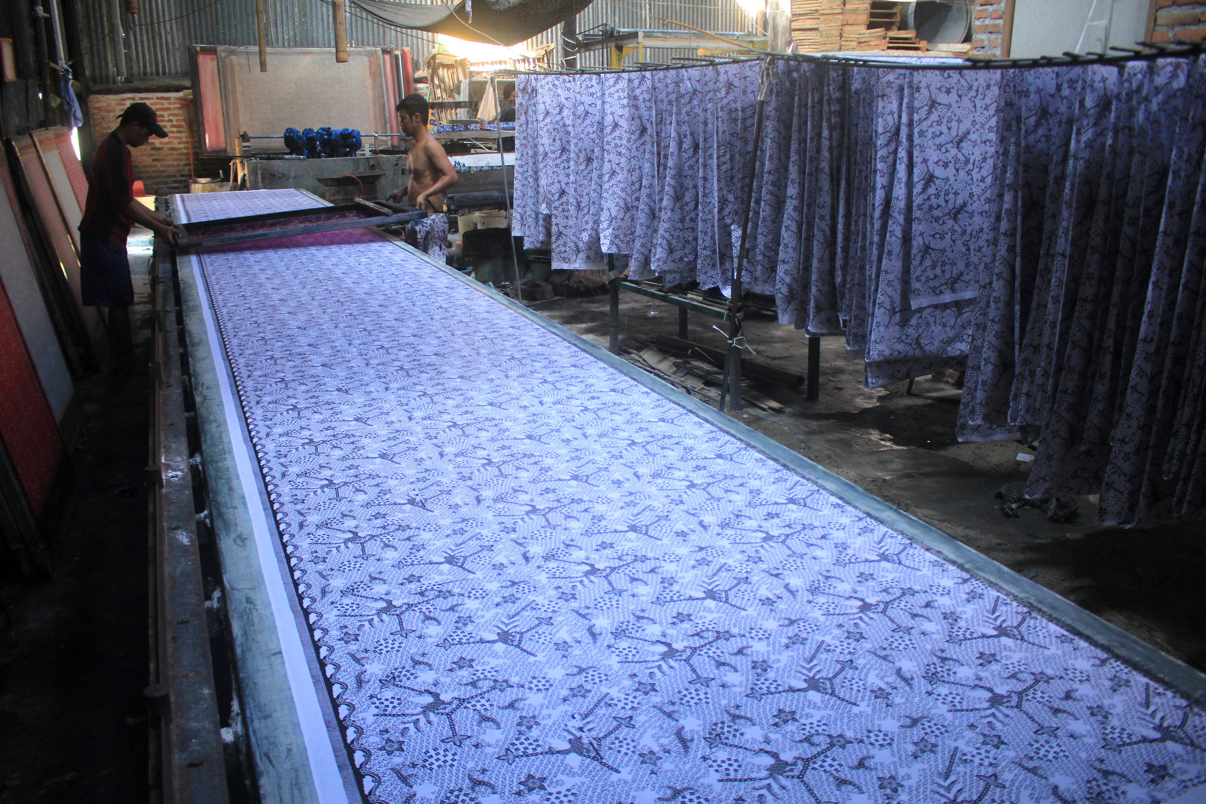 Ilustrasi: Pekerja menyelesaikan pembuatan batik sablon untuk bahan seragam 