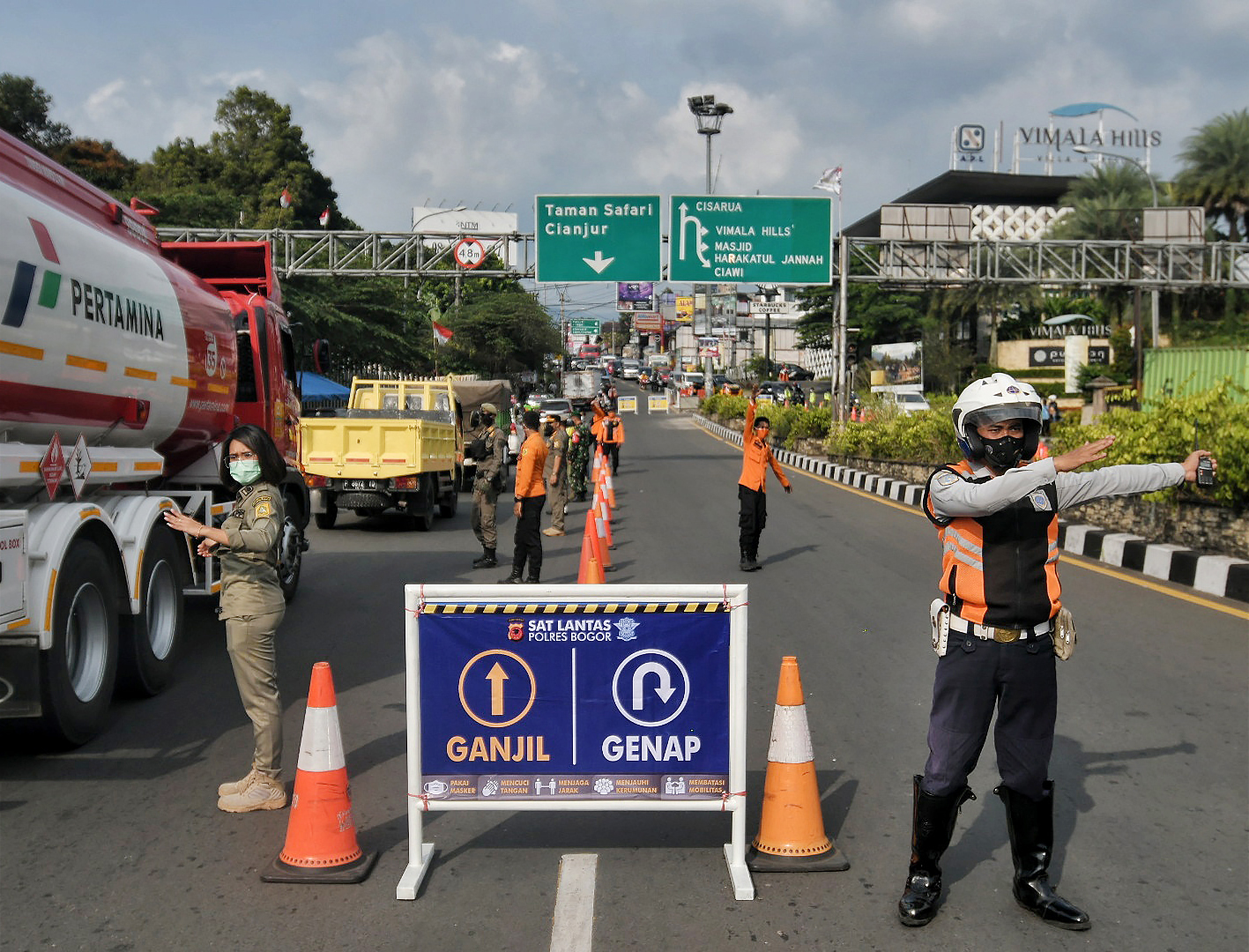 Petugas gabungan mengarahkan pengendara dengan plat nomer genap untuk memutar kendaraannya di Simpang Gadog, Bogor, Jawa Barat, Jumat (3/9).