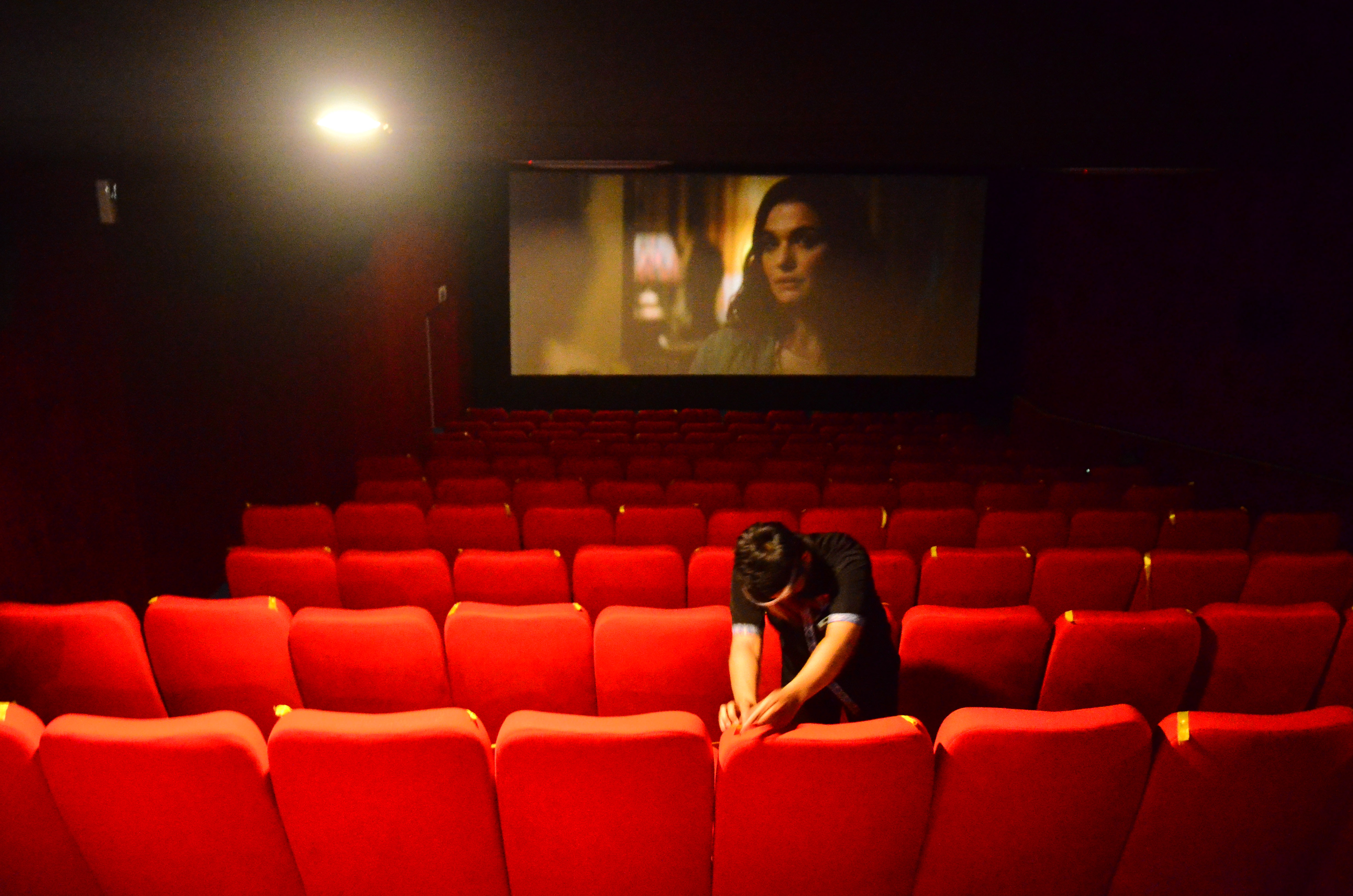 Petugas memasang pita jaga jarak di bioskop yang kembali dibuka pada PPKM level II