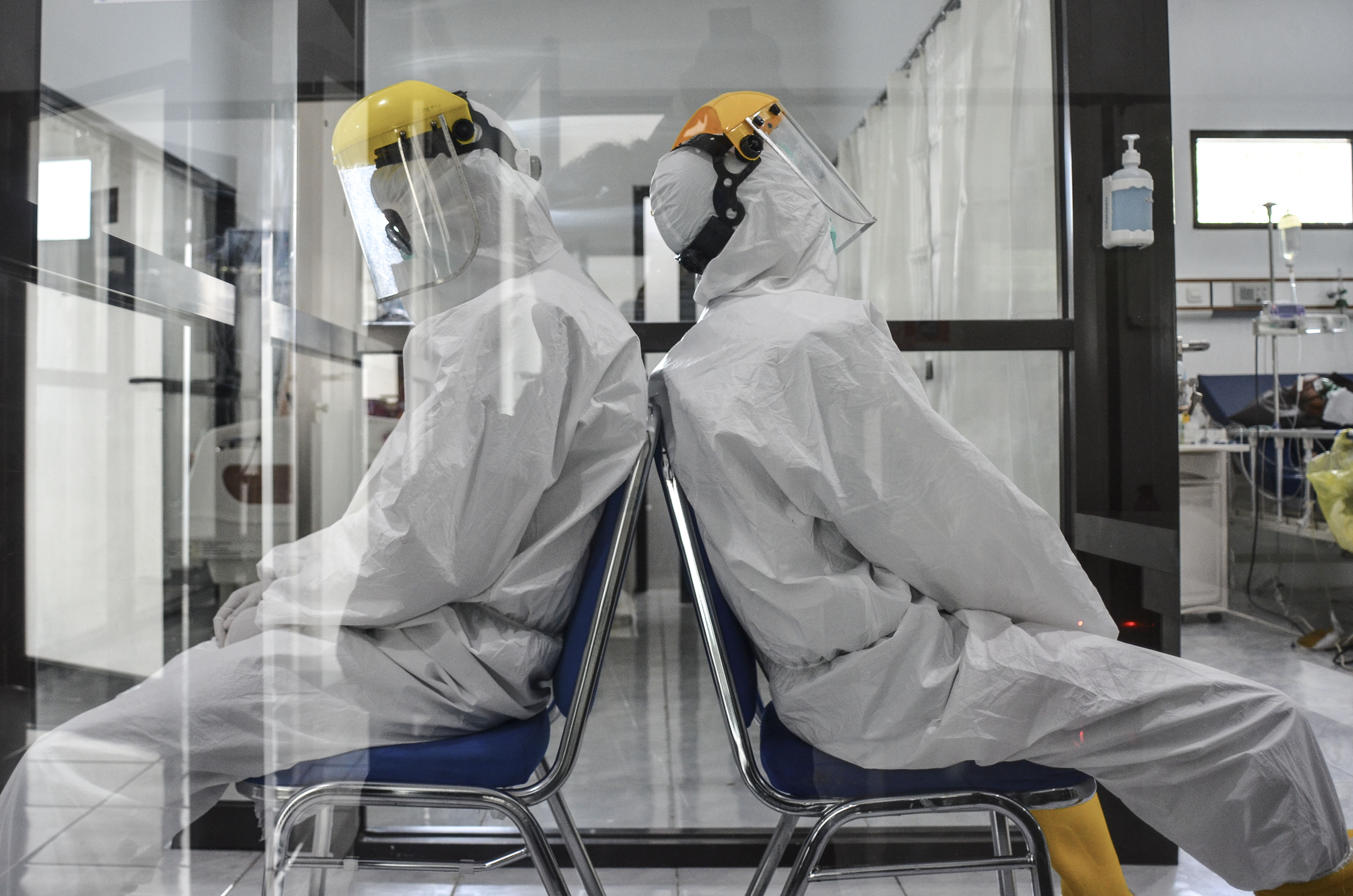 Dua tenaga kesehatan beristirahat sejenak saat menunggu pasien di ruang isolasi covid-19.