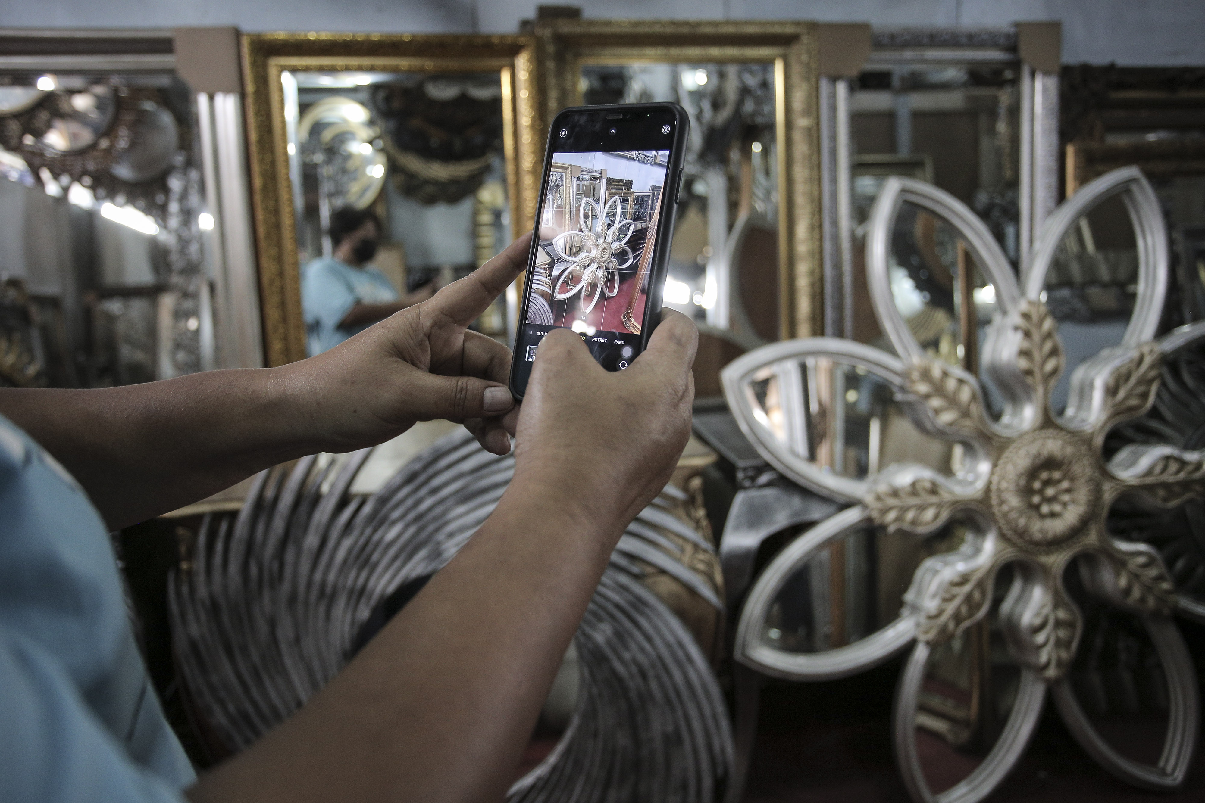 Pedagang cermin memotret salah satu produk yang akan dipasarkannya di aplikasi jual beli.