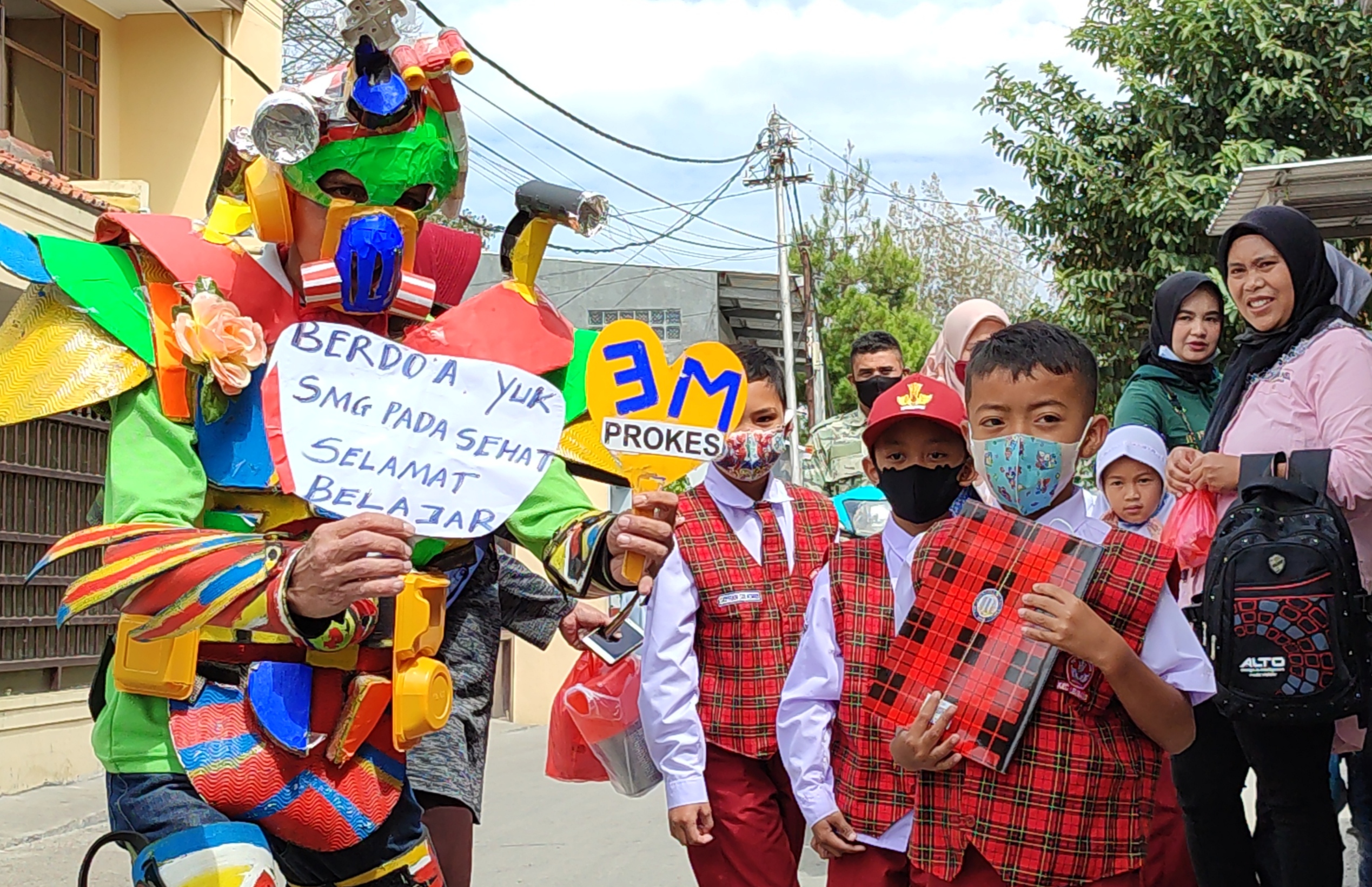 Soerang warga membagikan buku kepada pelajar di Lembang, Bandung Barat, dengan memakai kostum robot