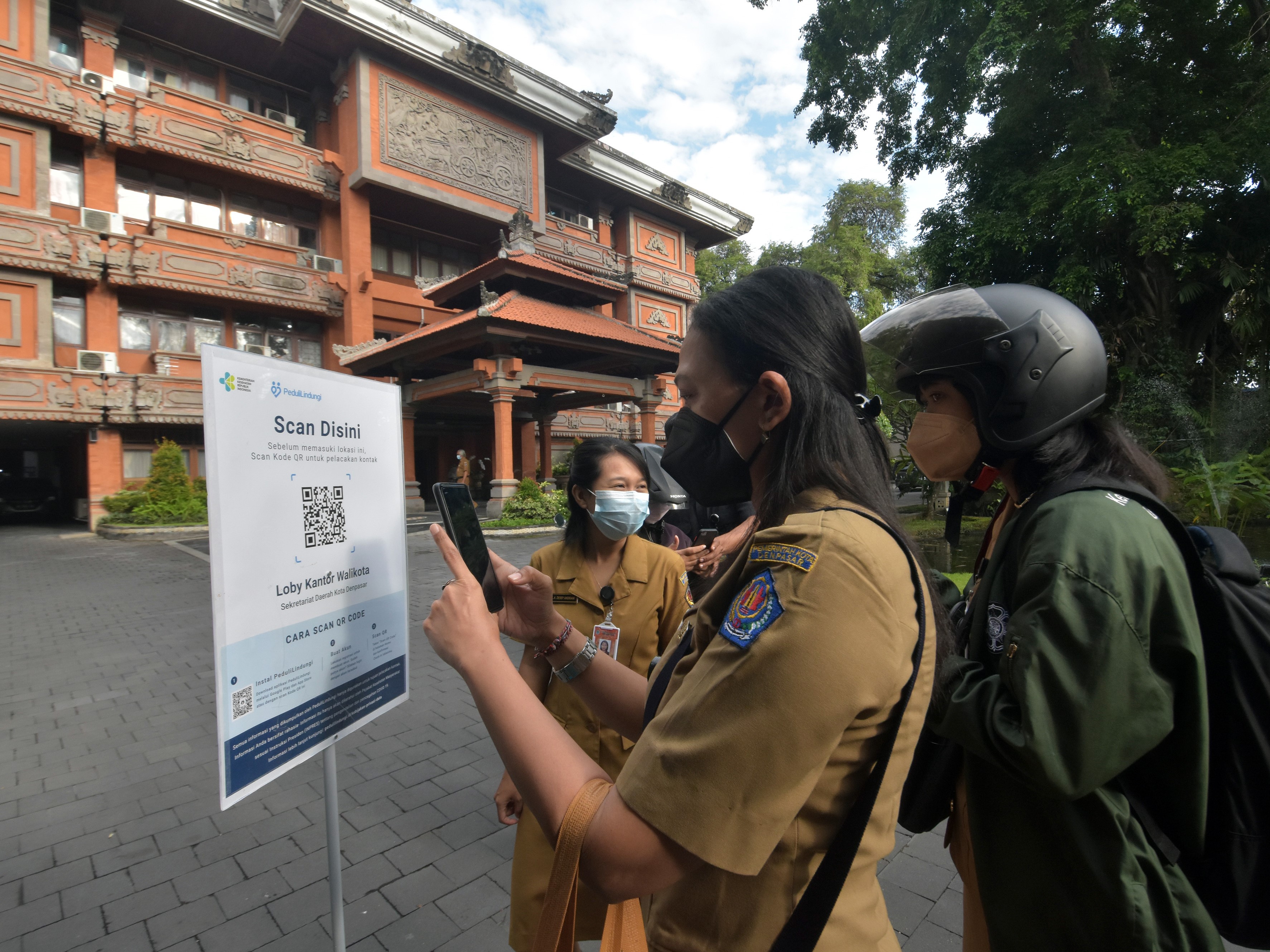 Sejumlah ASN melakukan pemindaian kode batang sertifikat vaksinasi menggunakan aplikasi PeduliLindungi saat akan memasuki kantor.
