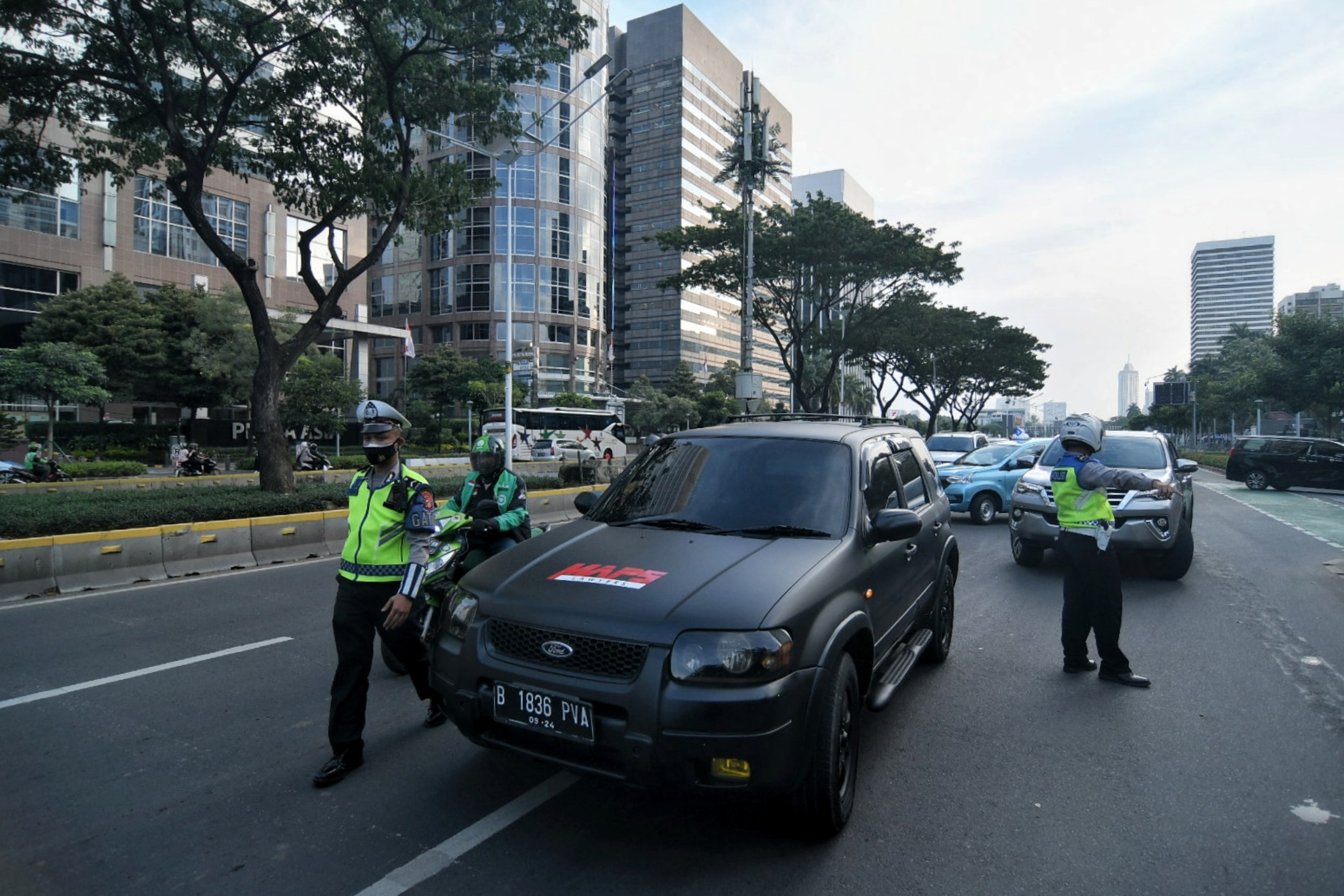 Petugas kepolisian melakukan penindakan pada kendaraan yang melanggar aturan ganjil genap di Jalan Sudirman, Jakarta, Rabu (1/9).