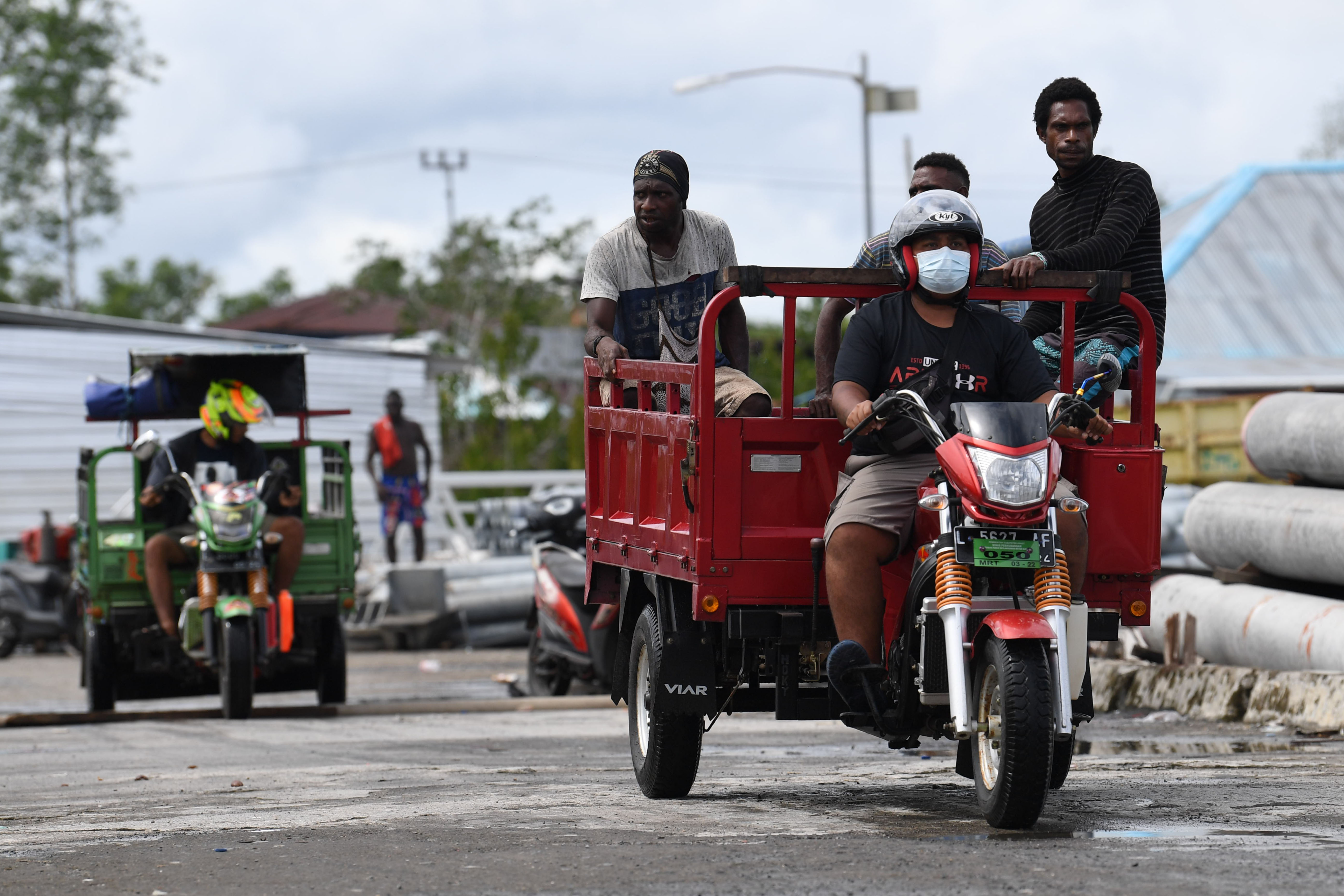 Warga mengendarai motor roda tiga untuk mengambil barang dari peti kemas di Pelabuhan Agats, Asmat, Papua.