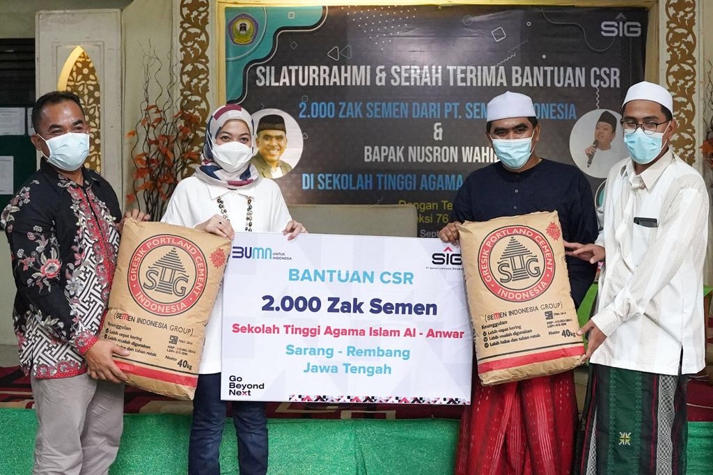 Corporate Secretary SIG, Vita Mahreyni (kedua kiri) bersama General Manager of CSR SIG (paling kiri) menyerahkan bantuan 2.000 zak semen.
