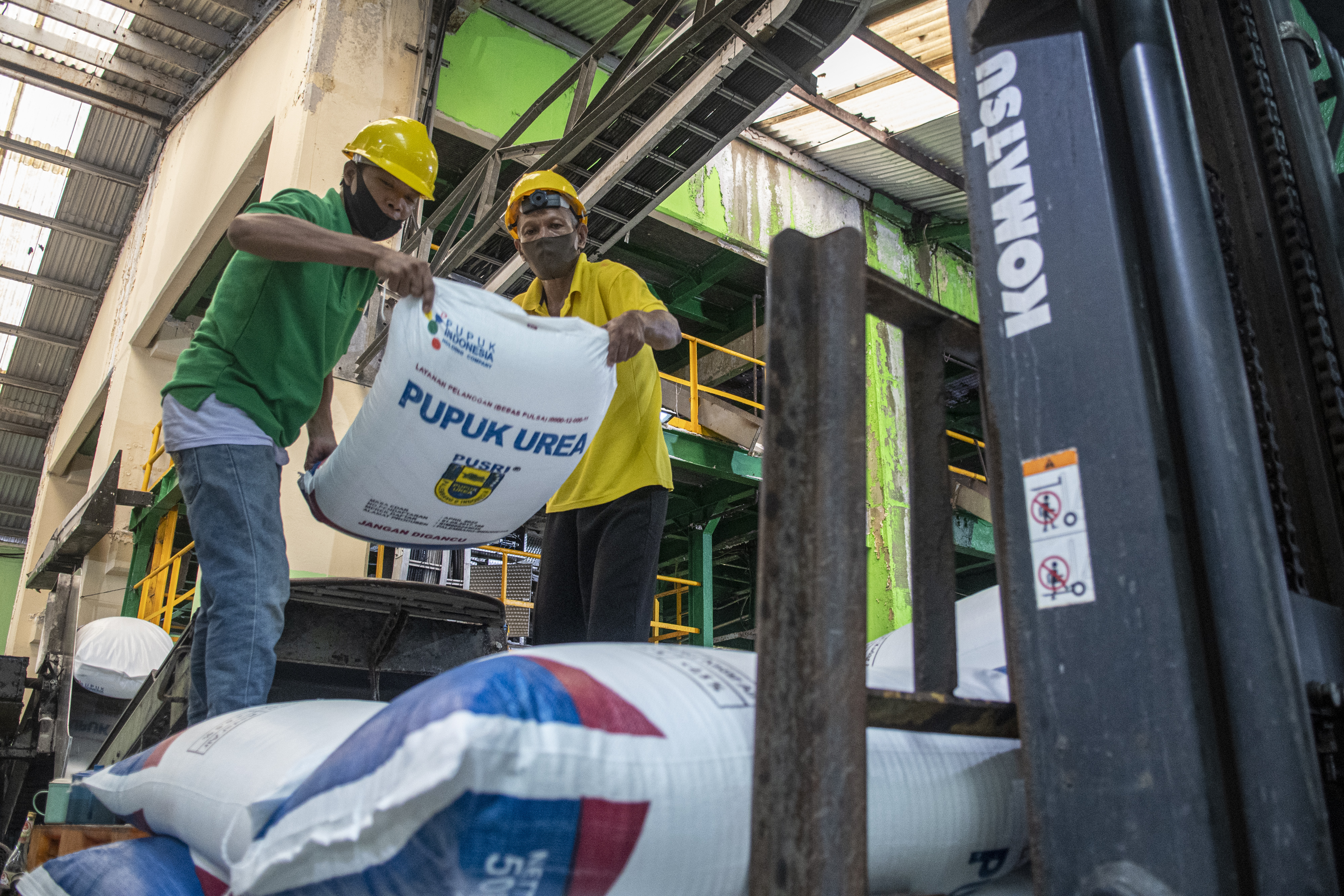 Pekerja menyusun tumpukan pupuk di pabrik pengantongan wilayah Sumatra Selatan.
