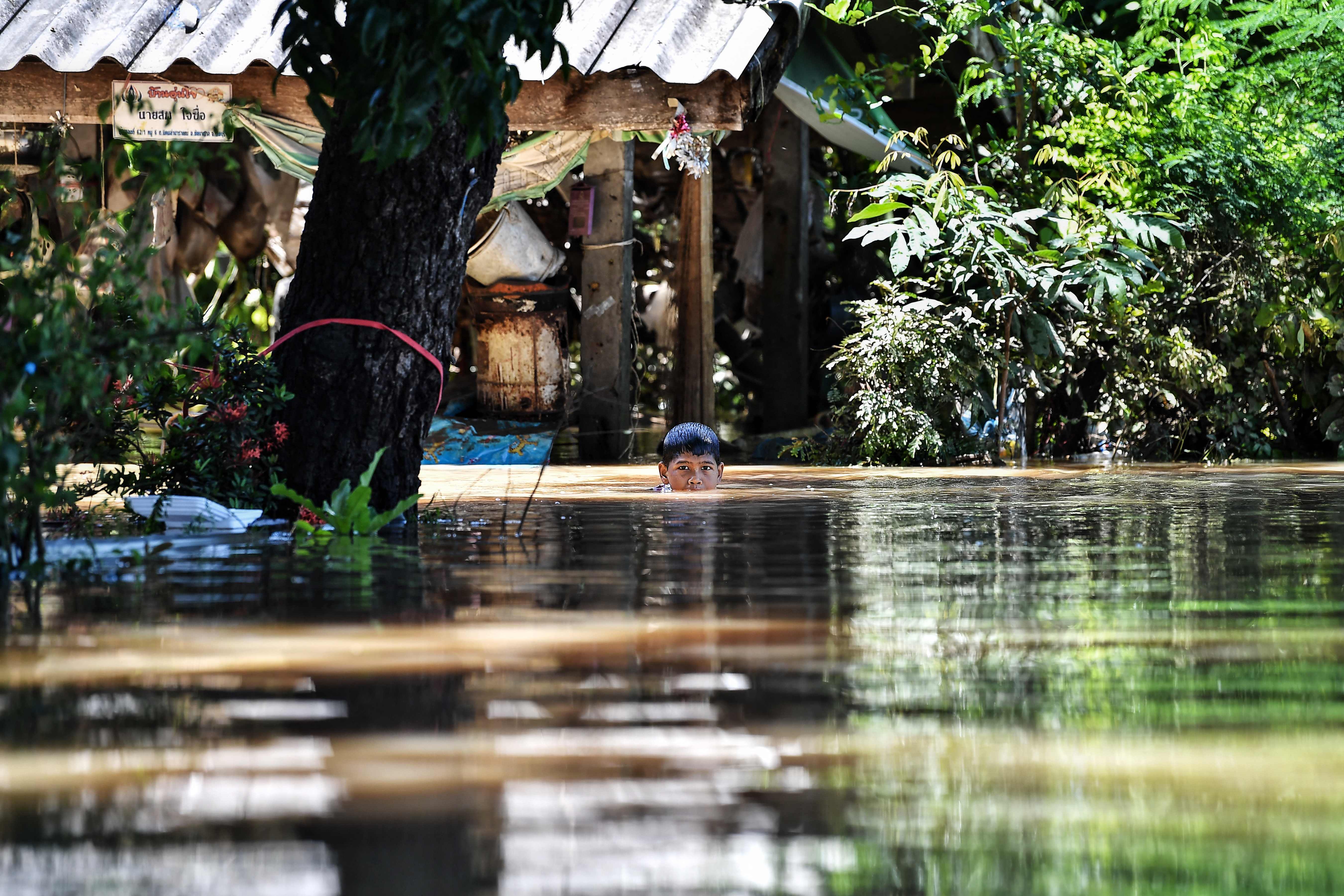 Seorang bocah berenang melintasi banjir yang melanda desanya di Provinsi Lopburi, Thailand.