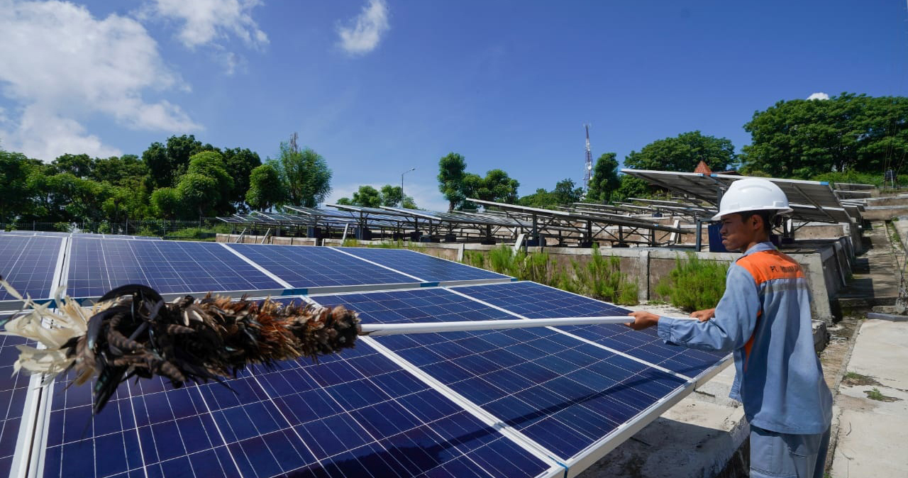 Pekerja membersihkan solar panel dari PLTS