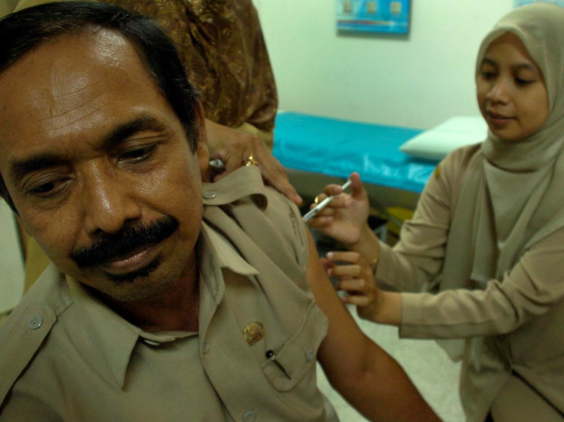 Seorang petugas dinas kesehatan menyuntikkan vaksin meningitis kepada seorang calon haji di RS Islam Surabaya.