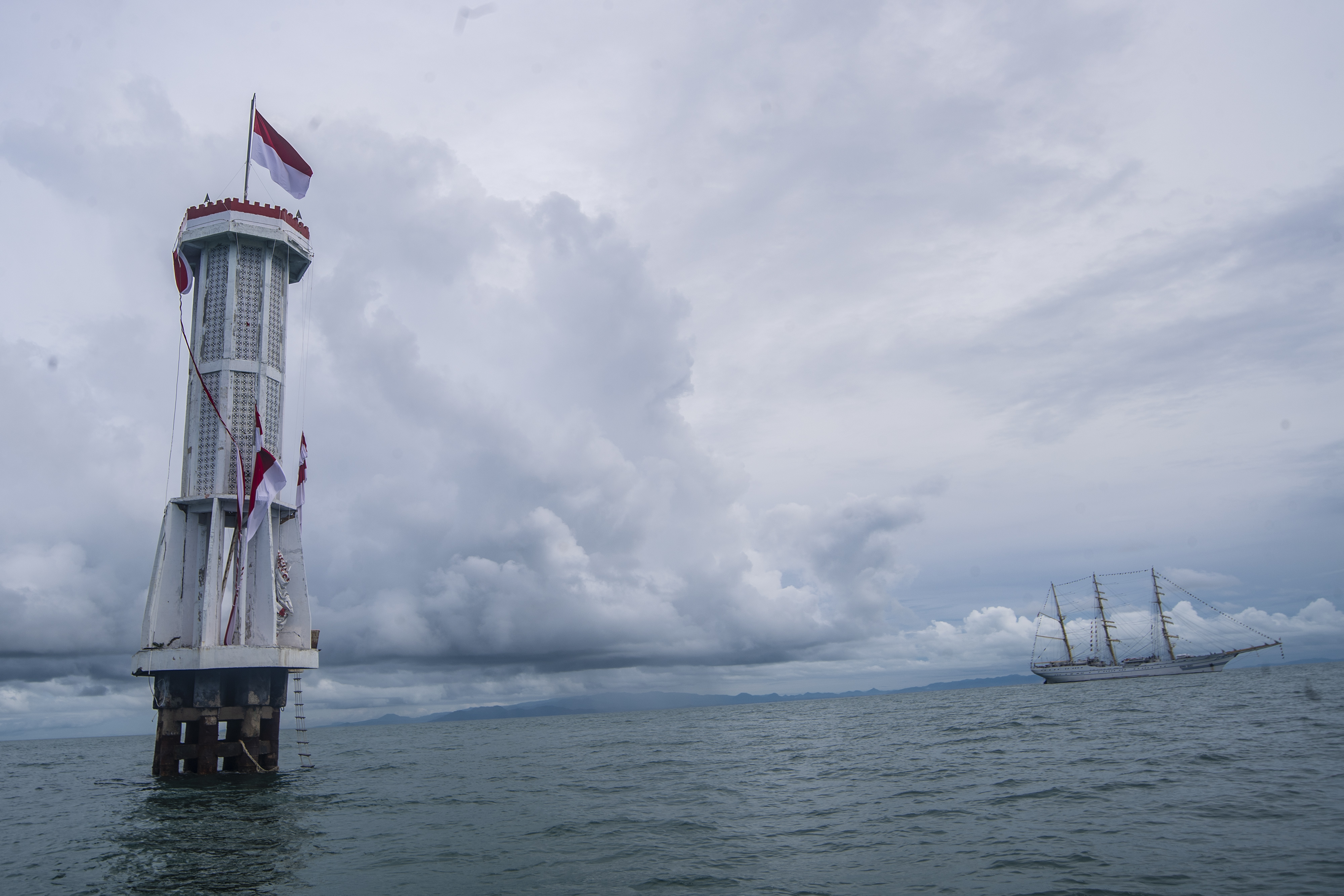 Ilustrasi bendera Merah Putih berkibar di mercusuar yang terletak di perairan Indonesia.