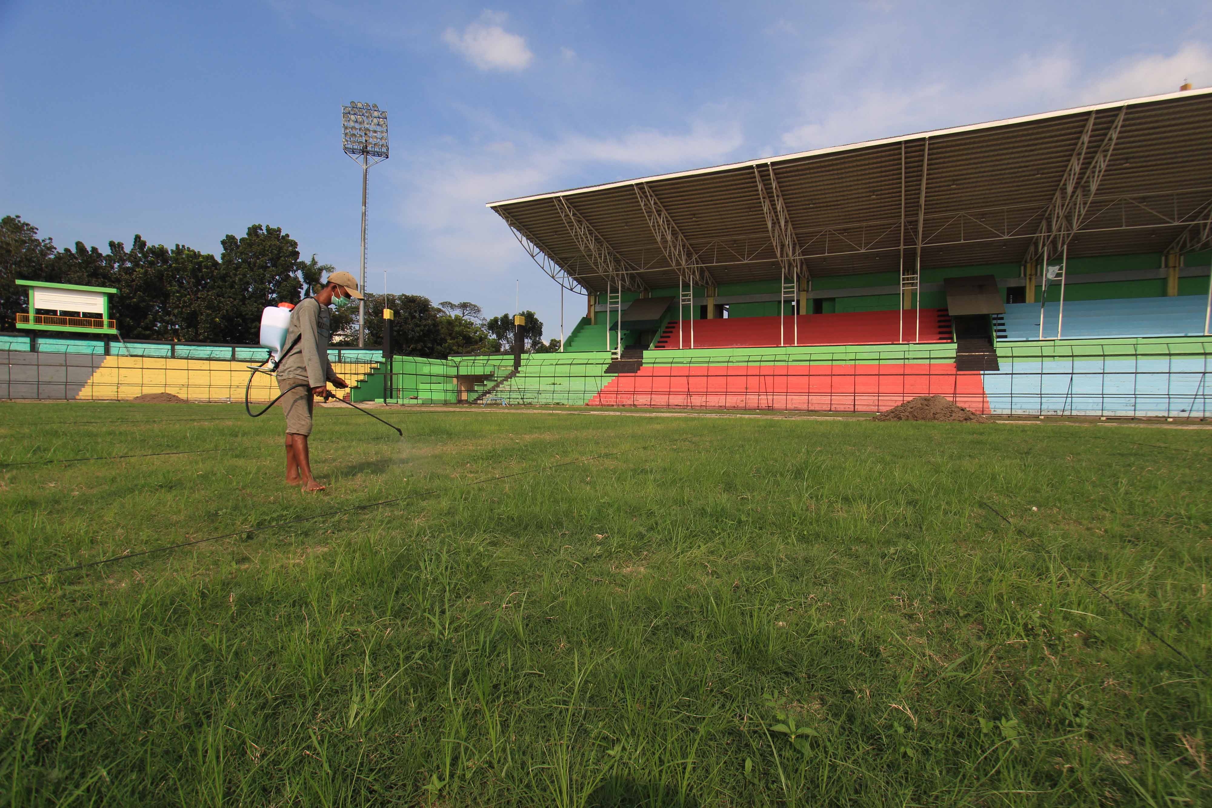 Seorang pekerja menyirami rumput lapangan Stadion Teladan dengan pupuk di Medan, Sumatra Utara.