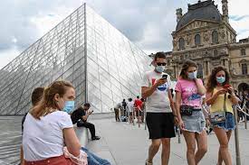  Warga mengenakan masker melintas di depan Pyramide du Louvre di Paris, Prancis.