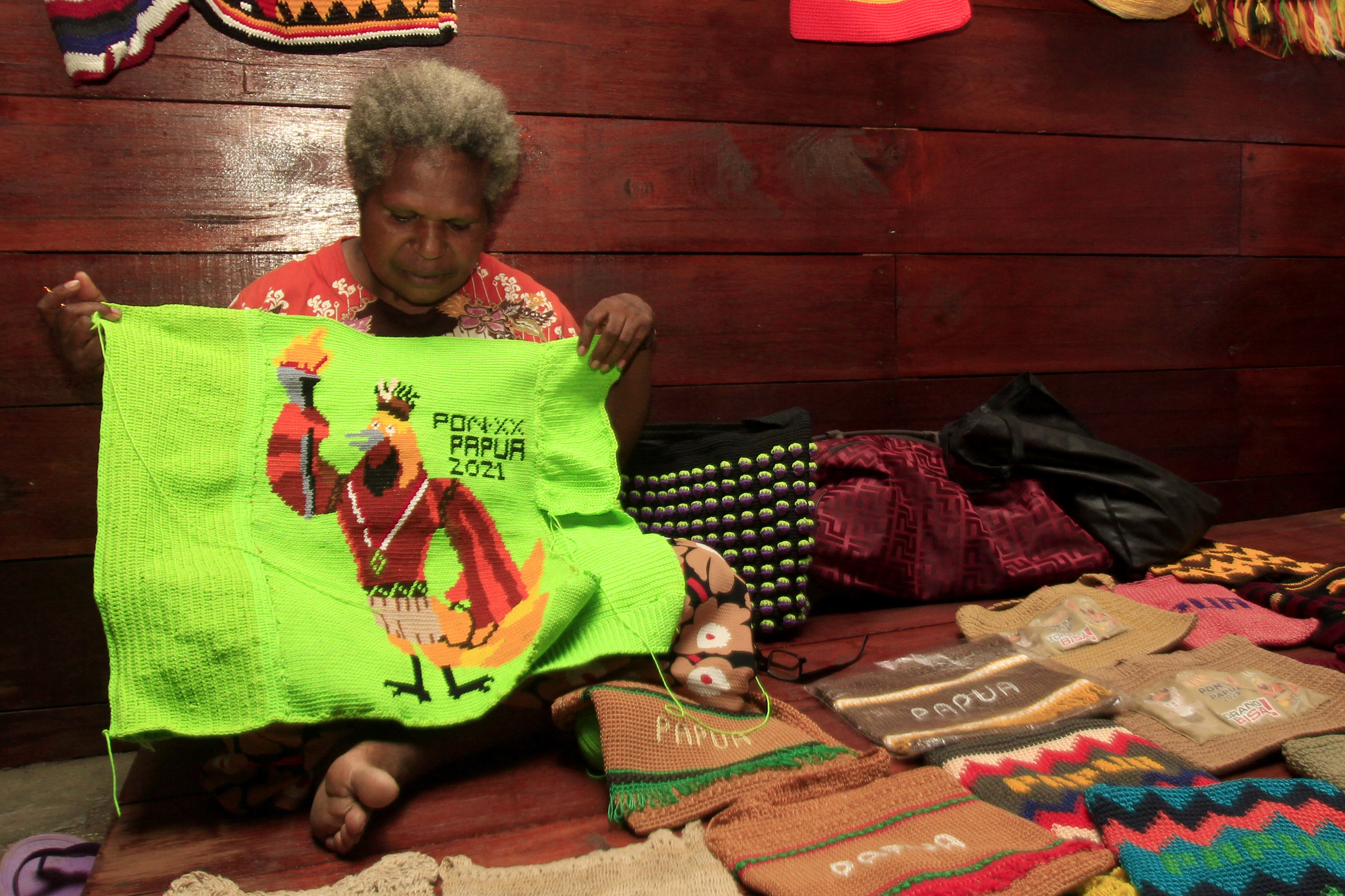 Seorang penjual menyelesaikan pembuatan noken bergambar Maskot PON XXI Papua di Galeri Noken Pusat Perbelanjaan Khas Papua, Distrik Abepura.