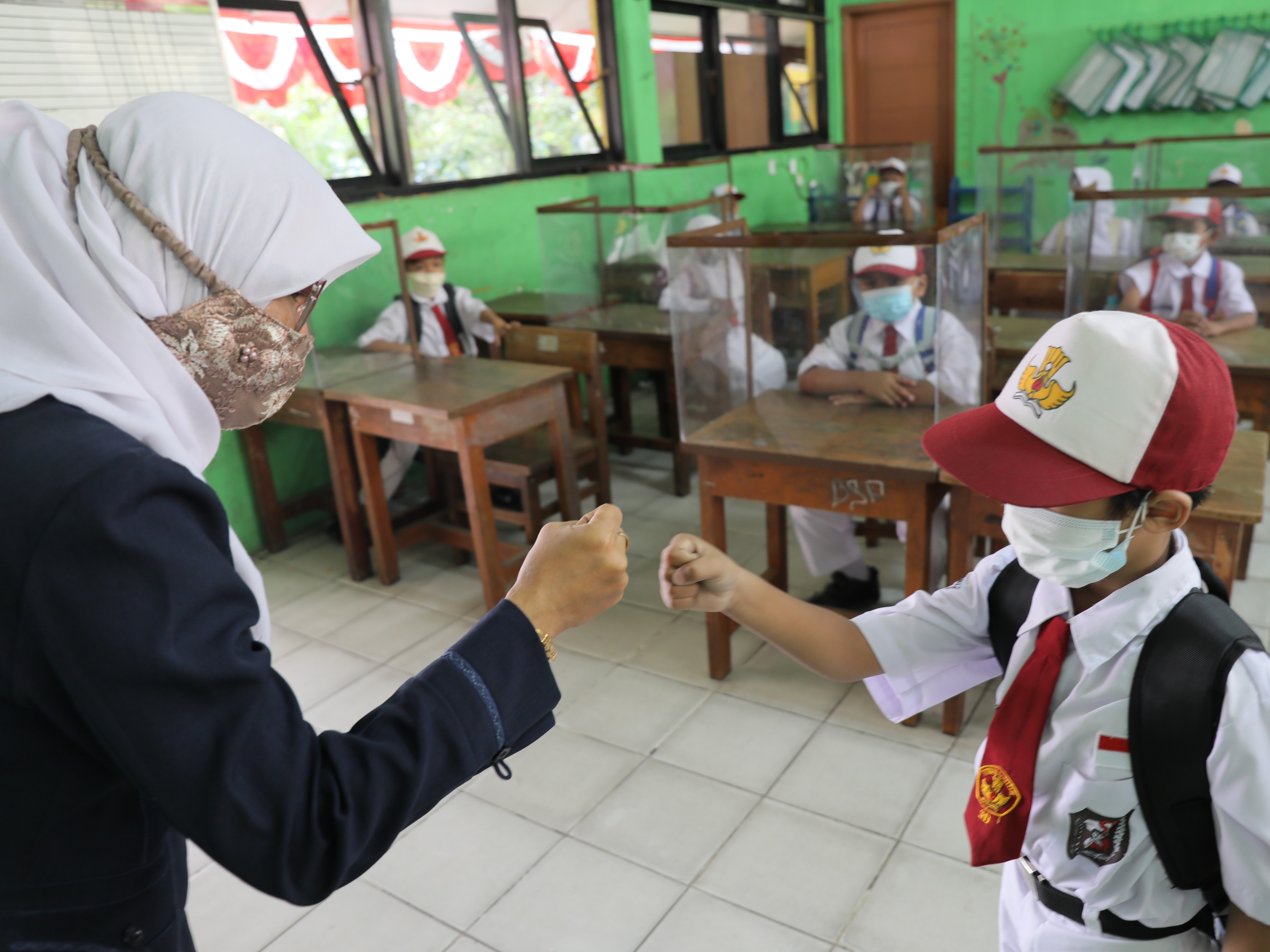Ibu Nuryanah memberikan salam kepada siswa kelas 1 seusai mengikuti pembelajaran tatap muka terbatas di SDN 05 Meruya Utara, Jakarta.