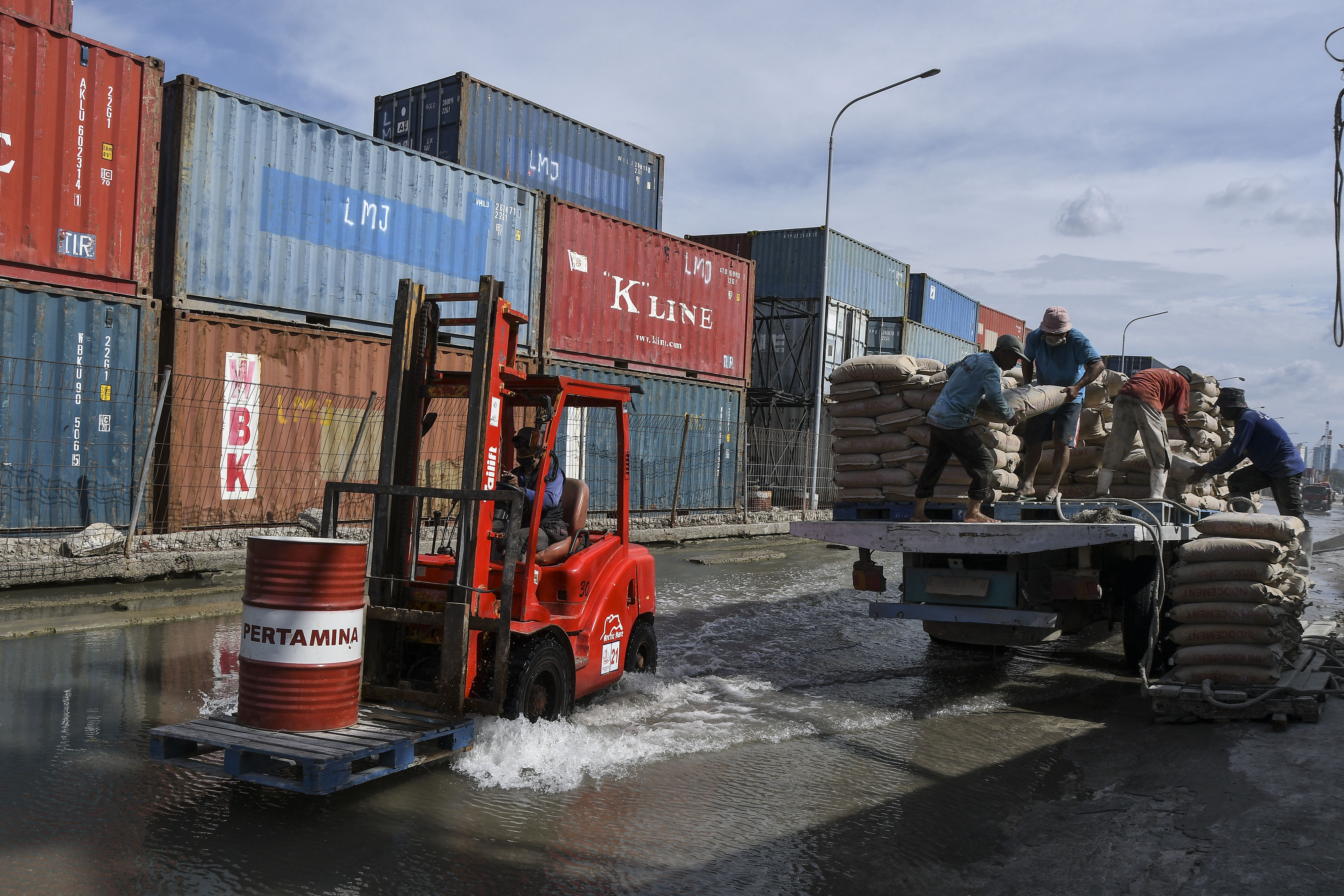 Sejumlah pekerja mengangkut muatan semen ke atas kapal saat banjir rob menggenangi Pelabuhan Sunda Kelapa, Jakarta Utara, Sabtu (16/1/2021).