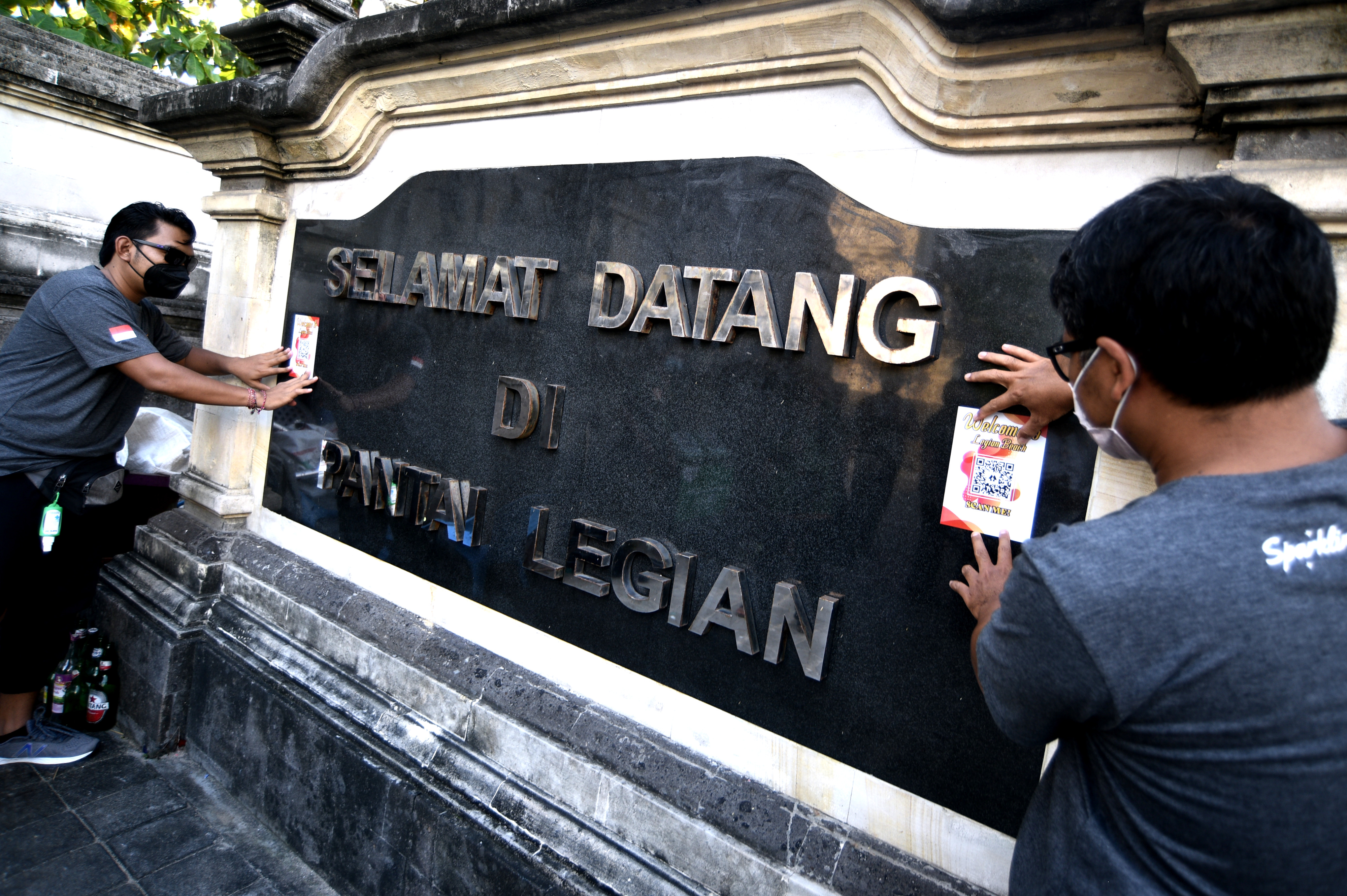  Petugas menempelkan stiker QR Code di kawasan wisata Pantai Legian, Badung, Bali, Sabtu (18/9/2021).
