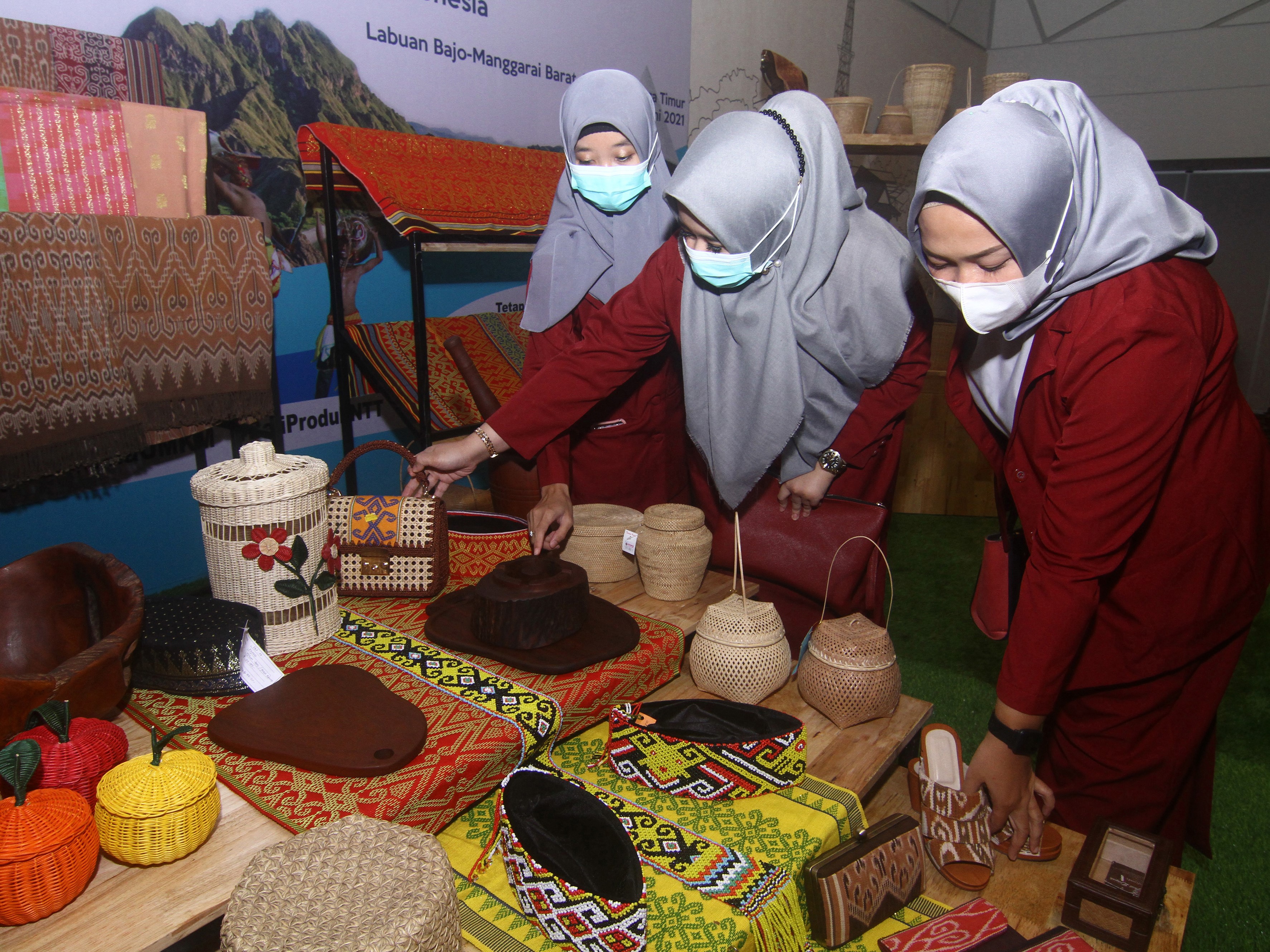 Tiga pengunjung mengamati kerajinan tangan UMKM yang dipamerkan pada kegiatan bertajuk Kilau Digital Flobamora.