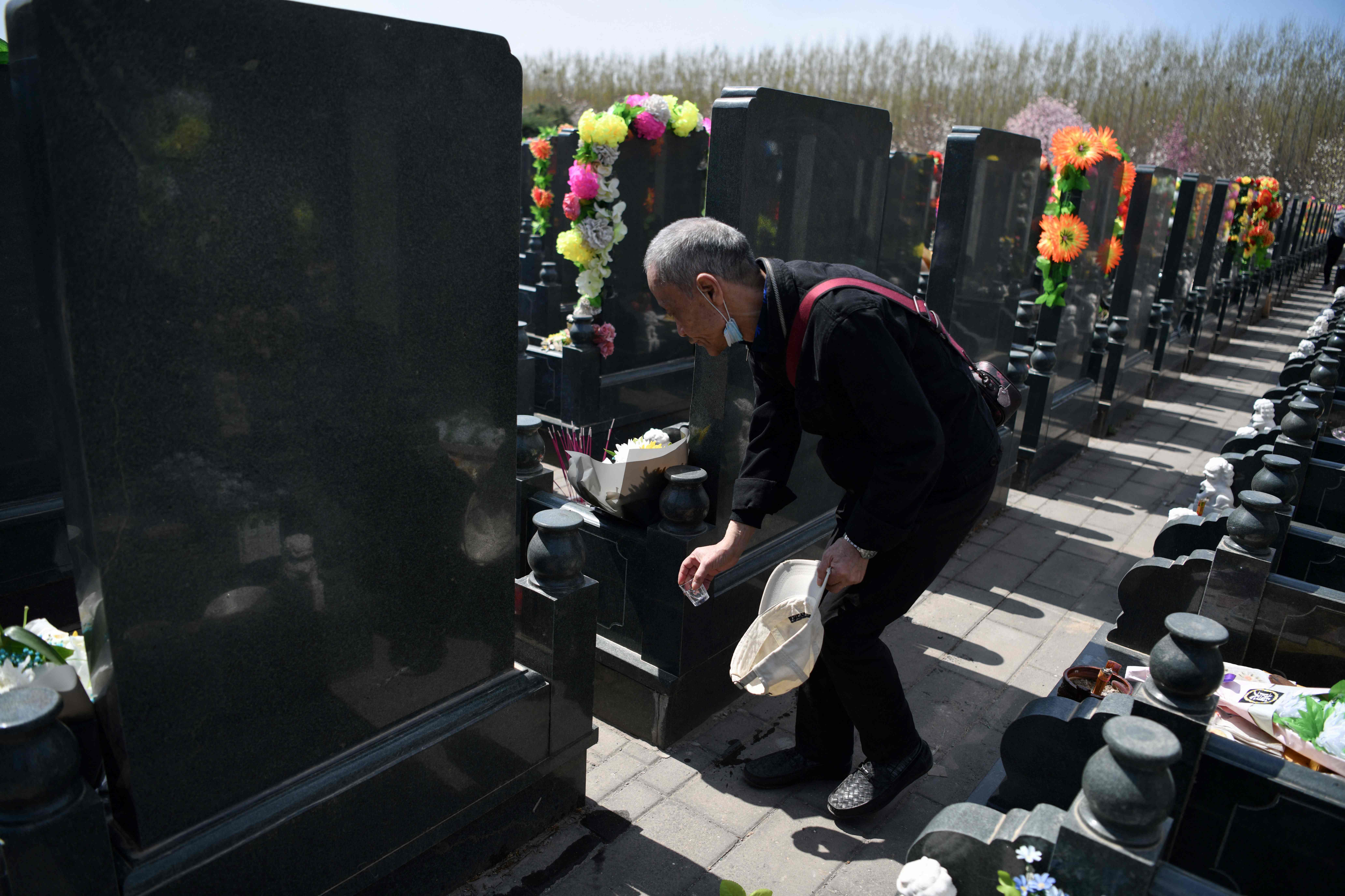 Seorang anggota keluarga meletakan alkohol di area pemakaman. Tradisi minum alkohol telah ada di Tiongkok sejak ribuan tahun silam.