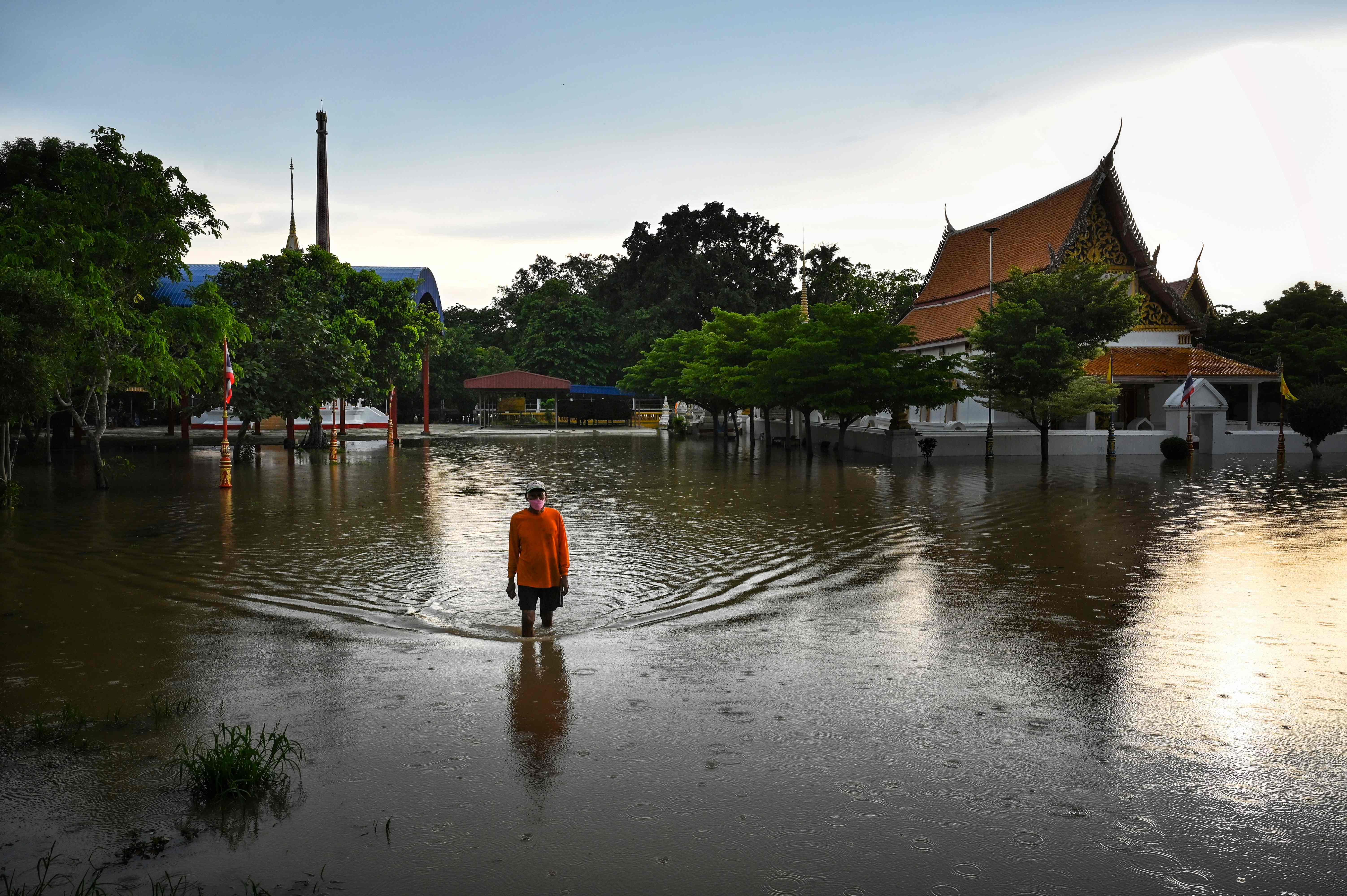 Seorang pria melewati banjir di depan sebuah kuil Buddha di provinsi Ayutthaya, Thailand tengah, Selasa (28/9/2021)