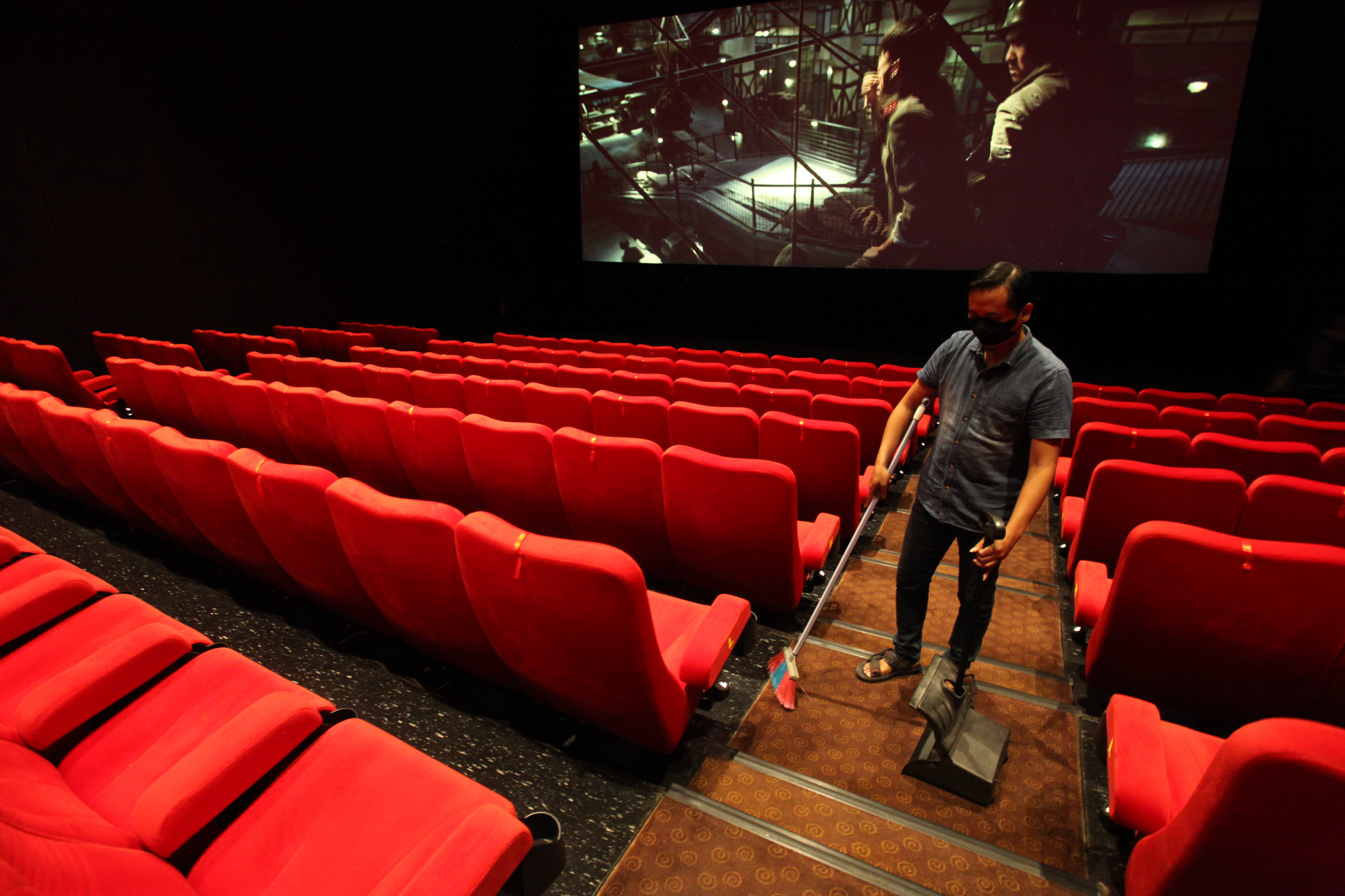 Pegawai bioskop merapikan ruang sinema