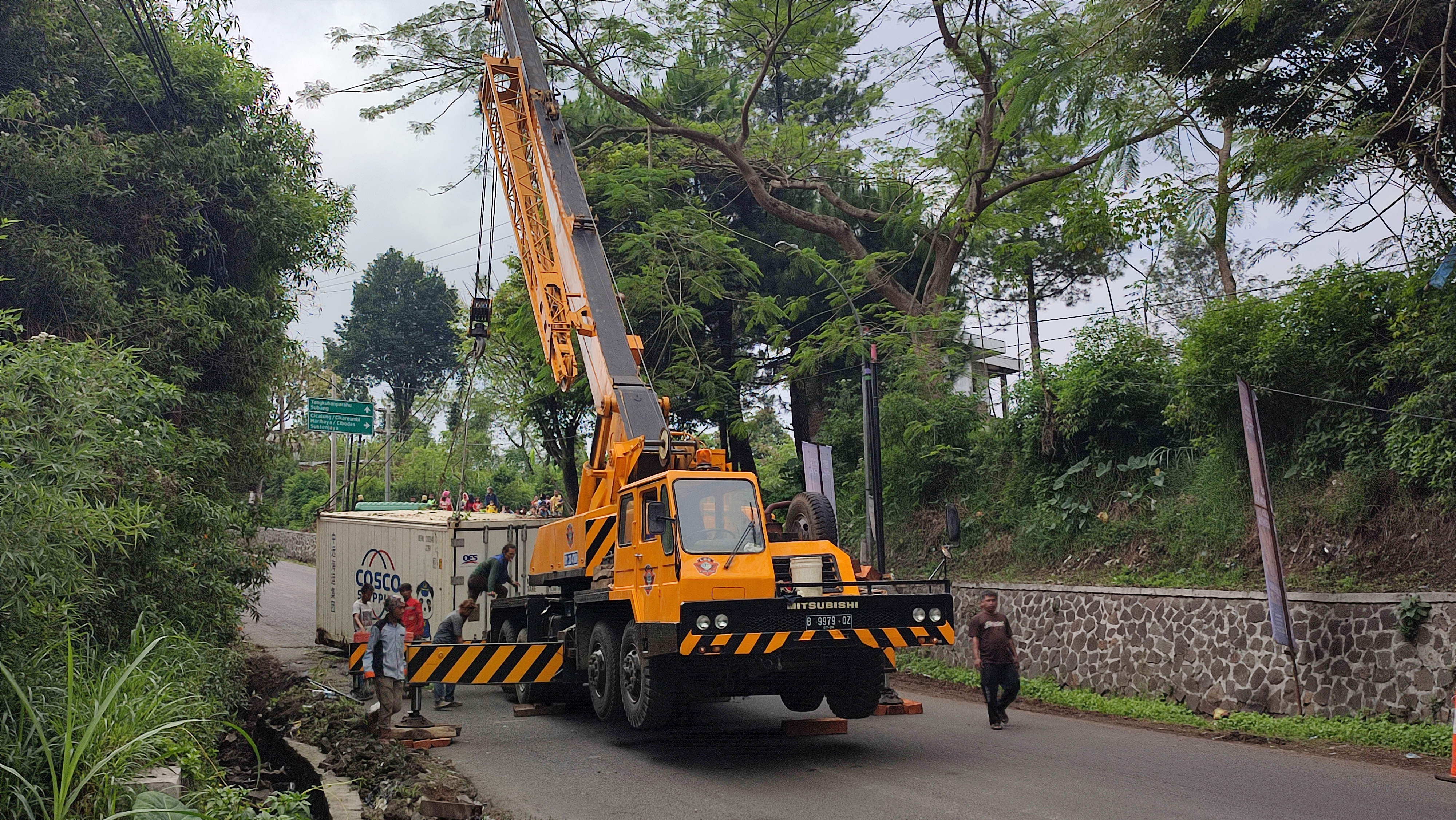 Alat berat berusaha menyingkirkan kontainer yang melintang di tengah jalan di wilayah Lembang, Bandung Barat