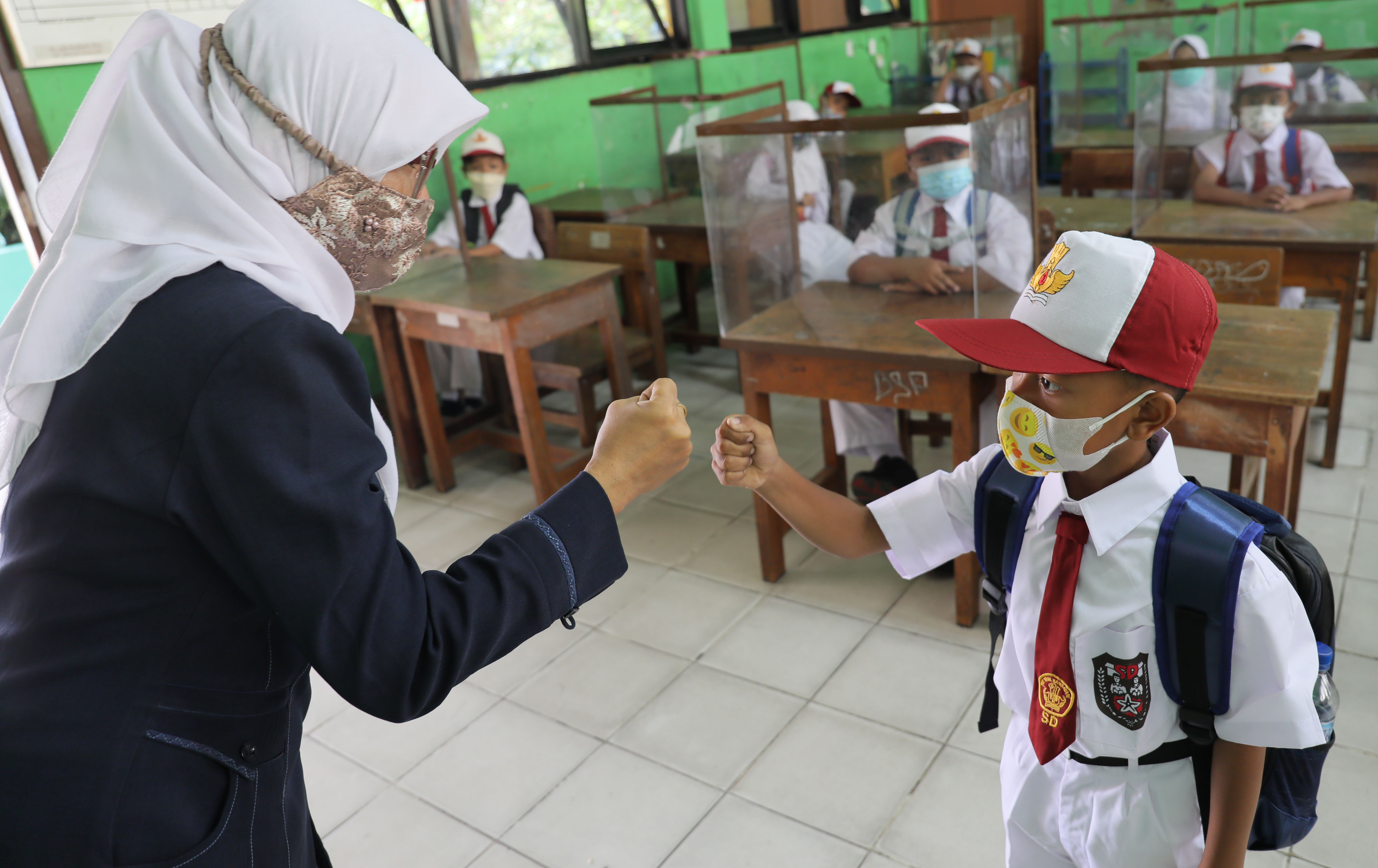 Guru memberikan salam kepada Siswa kelas 1 saat mengikuti PTM terbatas di SDN 05 Meruya Utara, Jakarta, Senin (6/9).