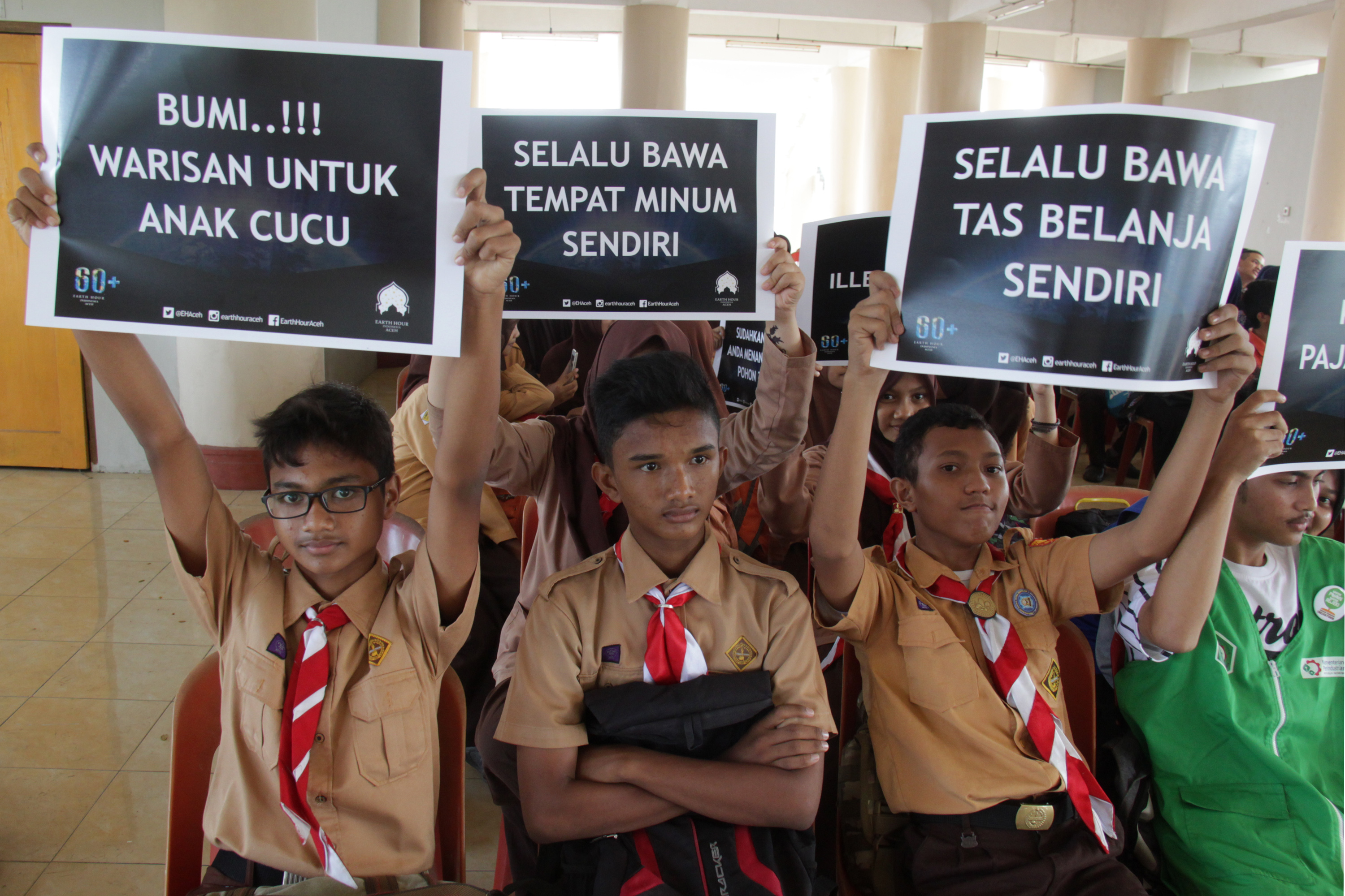 Pelajar mengangkat poster bertema lingkungan saat mengikuti pelajaran tentang mencintai dan melestarikan bumi di Banda Aceh.