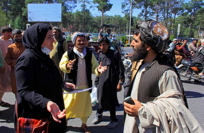 Seorang perempuan peserta aksi protes berbicara dengan pejuang Taliban.