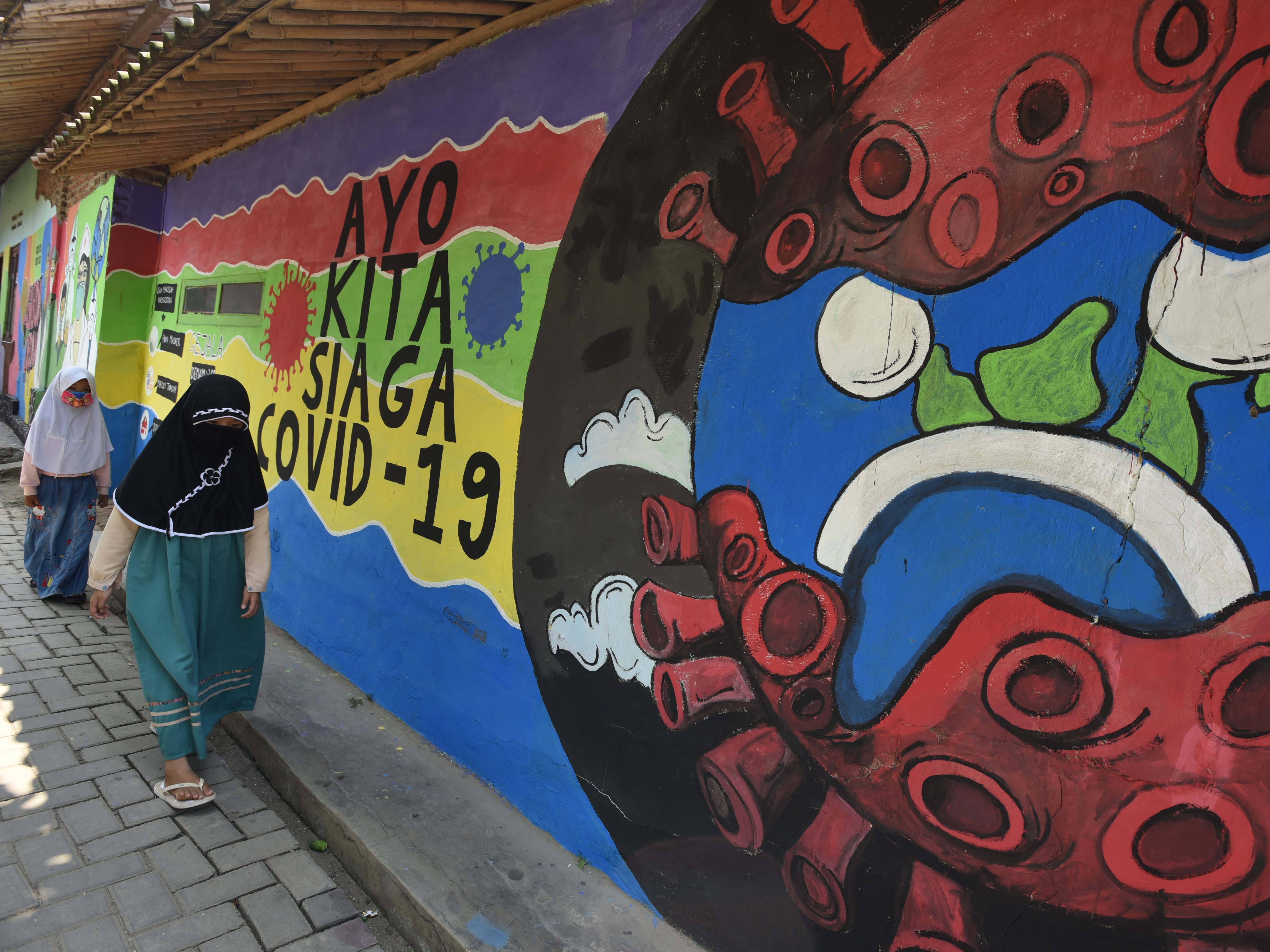 Anak melintas dekat mural Siaga Covid-19 di Walantaka, Serang, Banten.