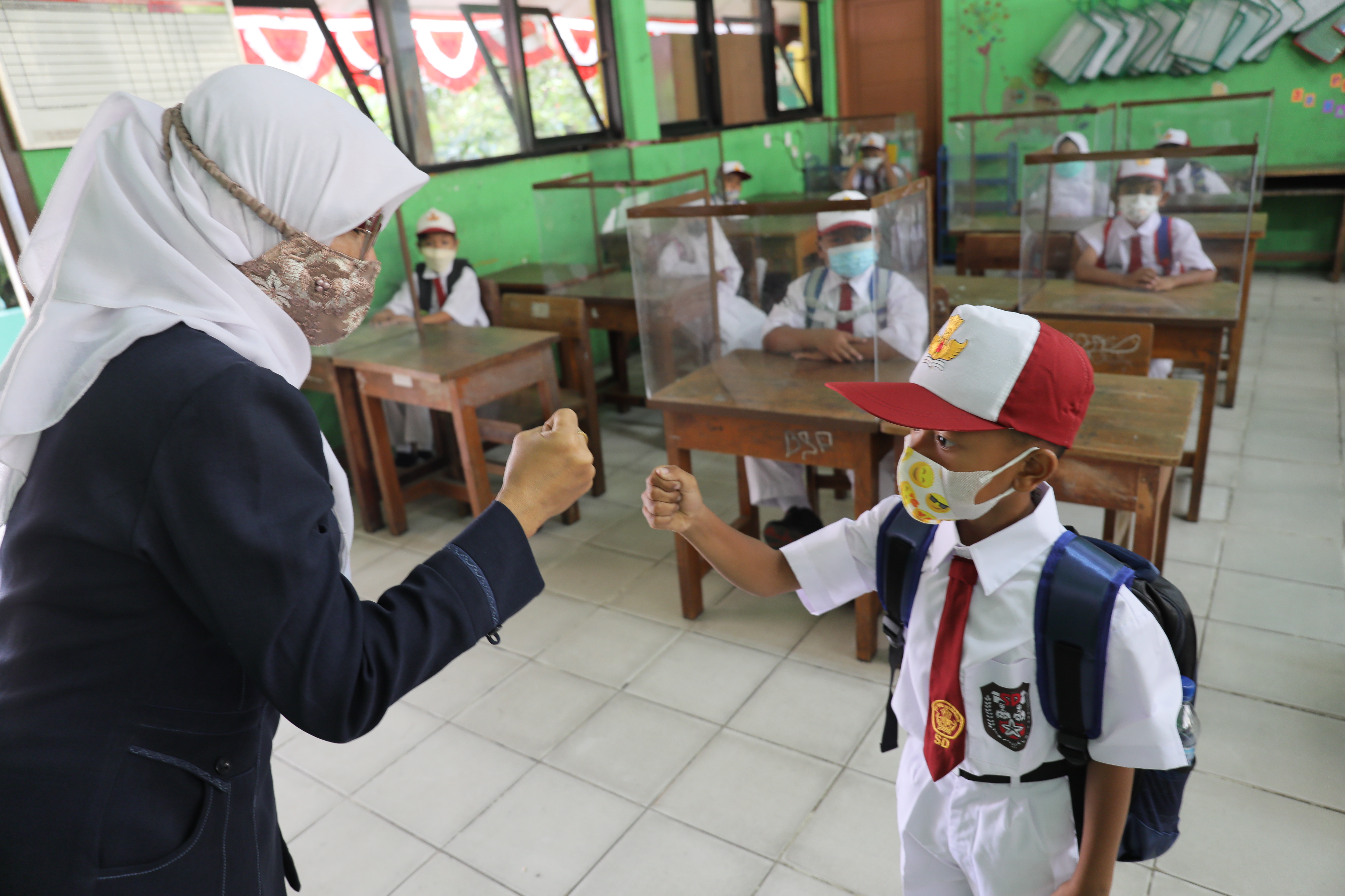 Ibu Nuryanah memberikan salam kepada Siswa kelas 1 seusai mengikuti pembelajaran tatap muka (PTM) terbatas di SDN 05 Meruya Utara, Jakarta.