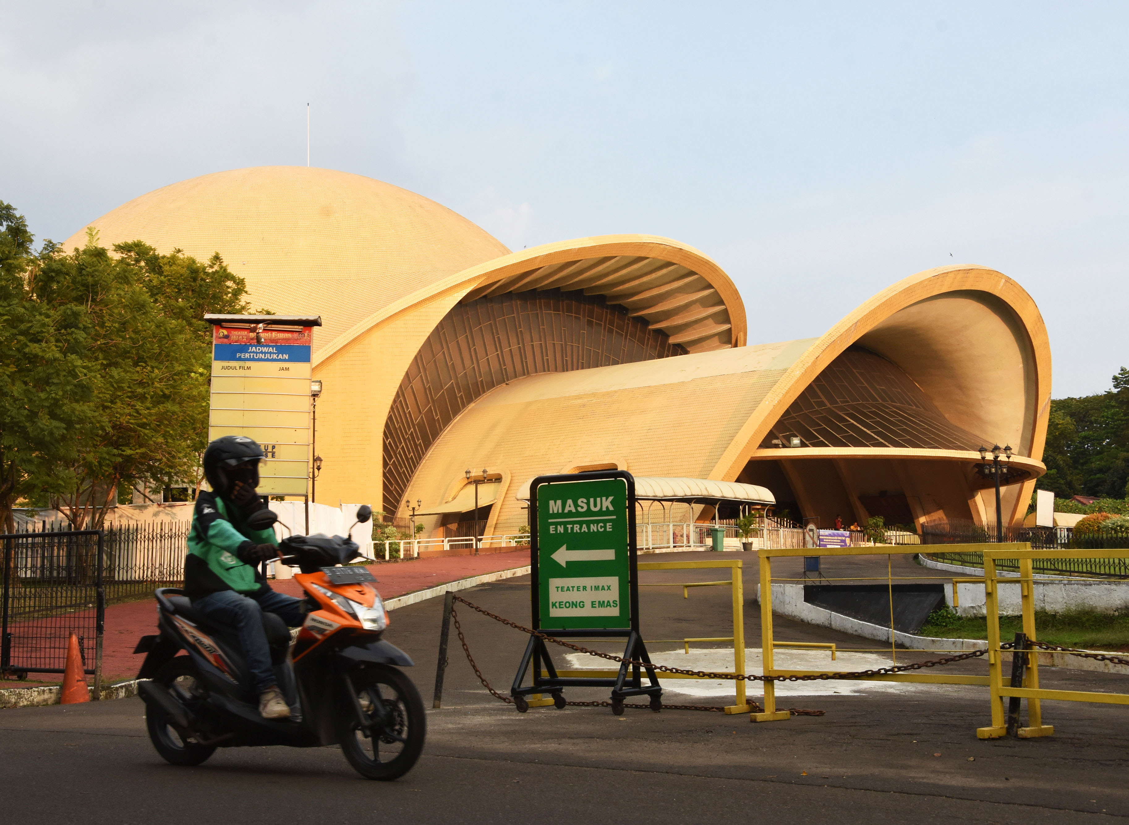  Pengendara ojek daring melintas di depan anjungan Keong Emas, Taman Mini Indonesia Indah (TMII), Jakarta.