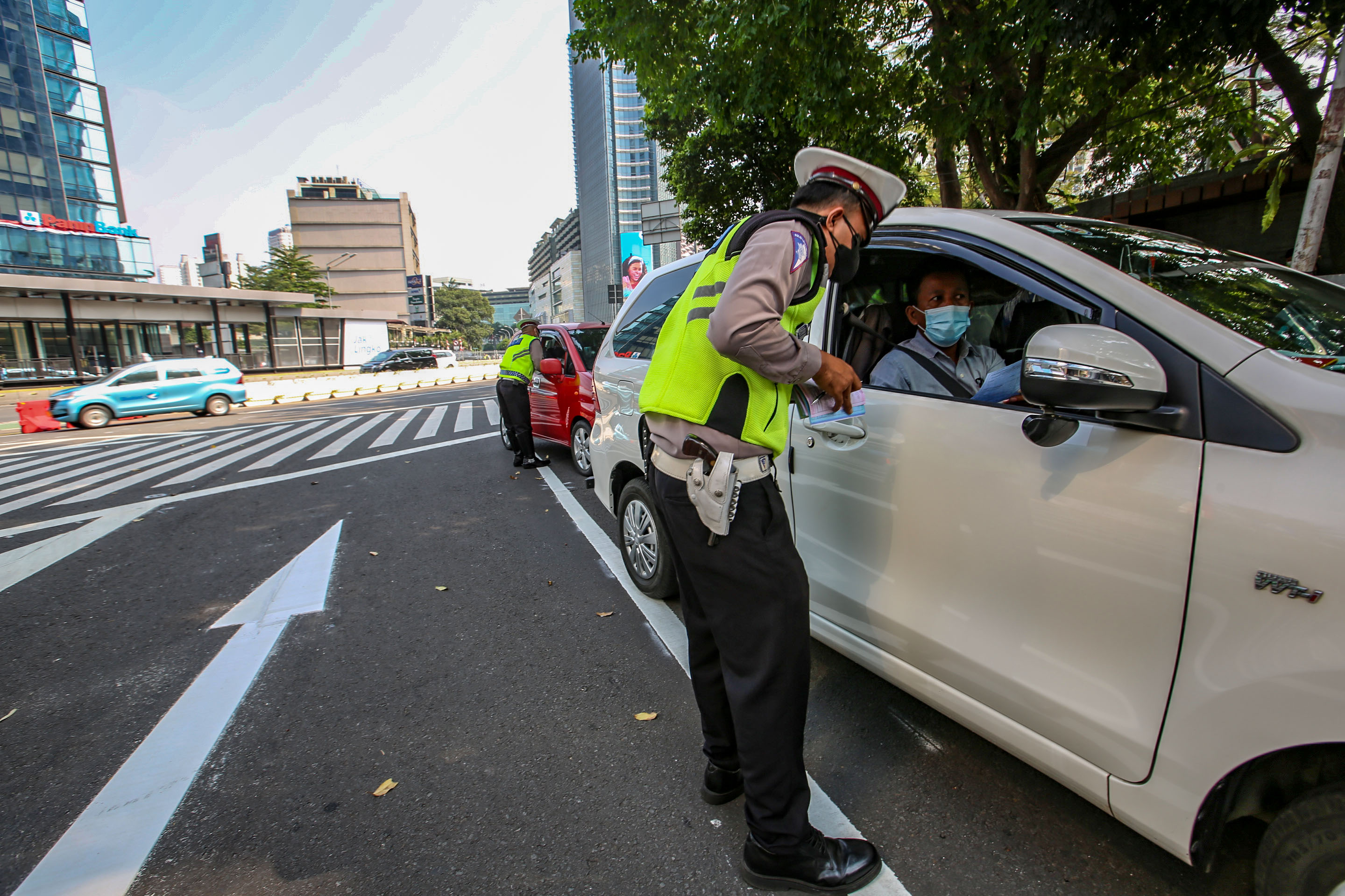  Petugas kepolisian memberikan sanksi tilang kepada pengendara roda empat yang melanggar aturan ganjil genap di kawasan Jalan Sudirman.
