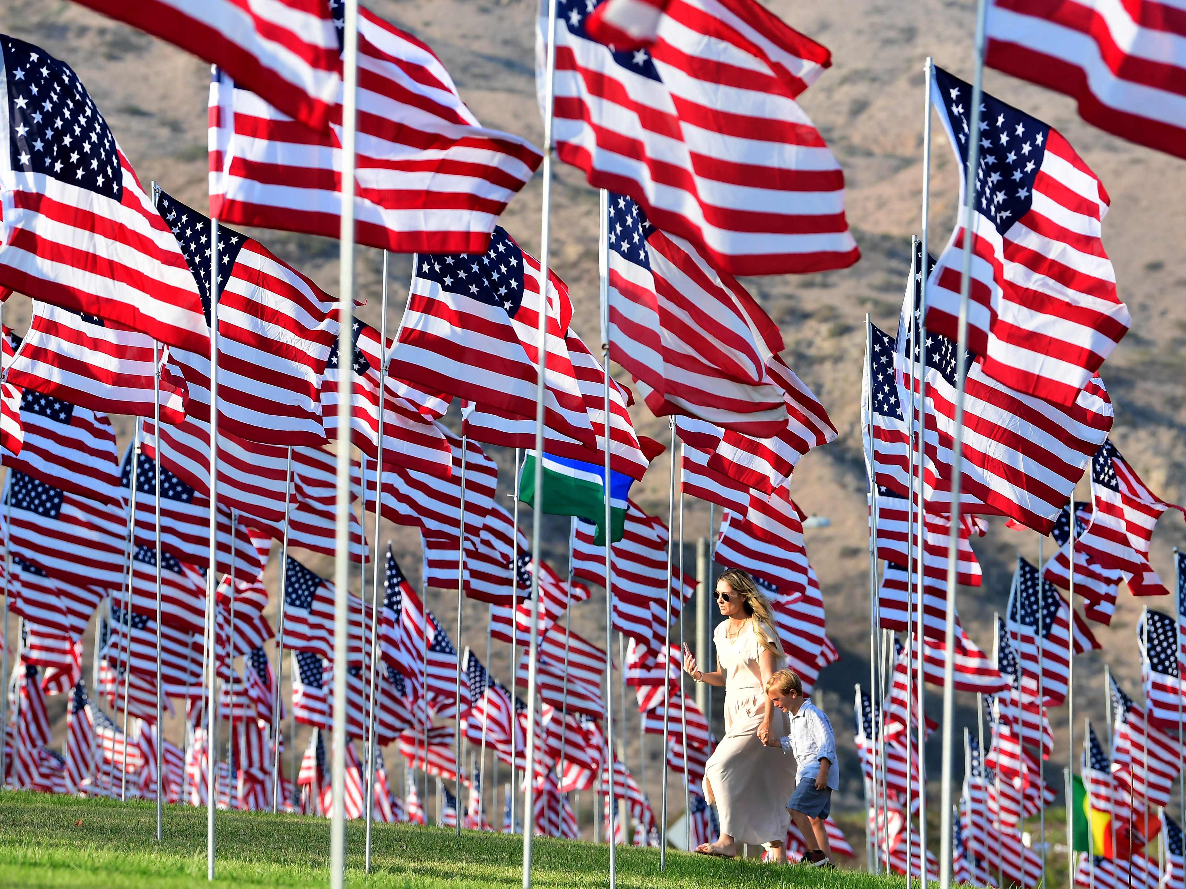 Seorang wanita dan anak berjalan melewati pajangan bendera AS untuk memperingati 20 tahun serangan 9/11 atau 11 September.