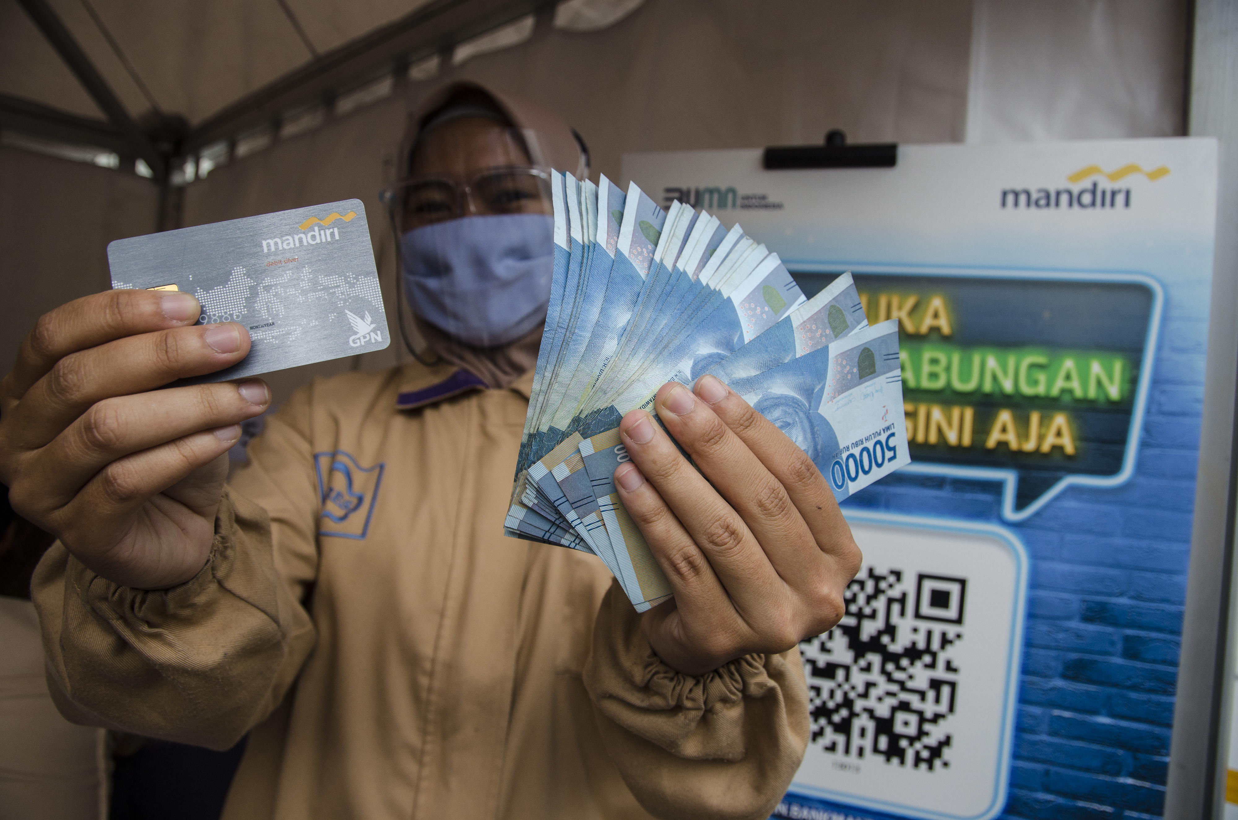 Pekerja menunjukkan kartu ATM dan uang saat menerima BSU di Kabupaten Bandung, Jawa Barat.