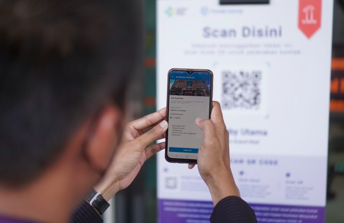 Pengunjung melakukan pemindaian QR code melalui aplikasi PeduliLindungi saat akan memasuki mal.