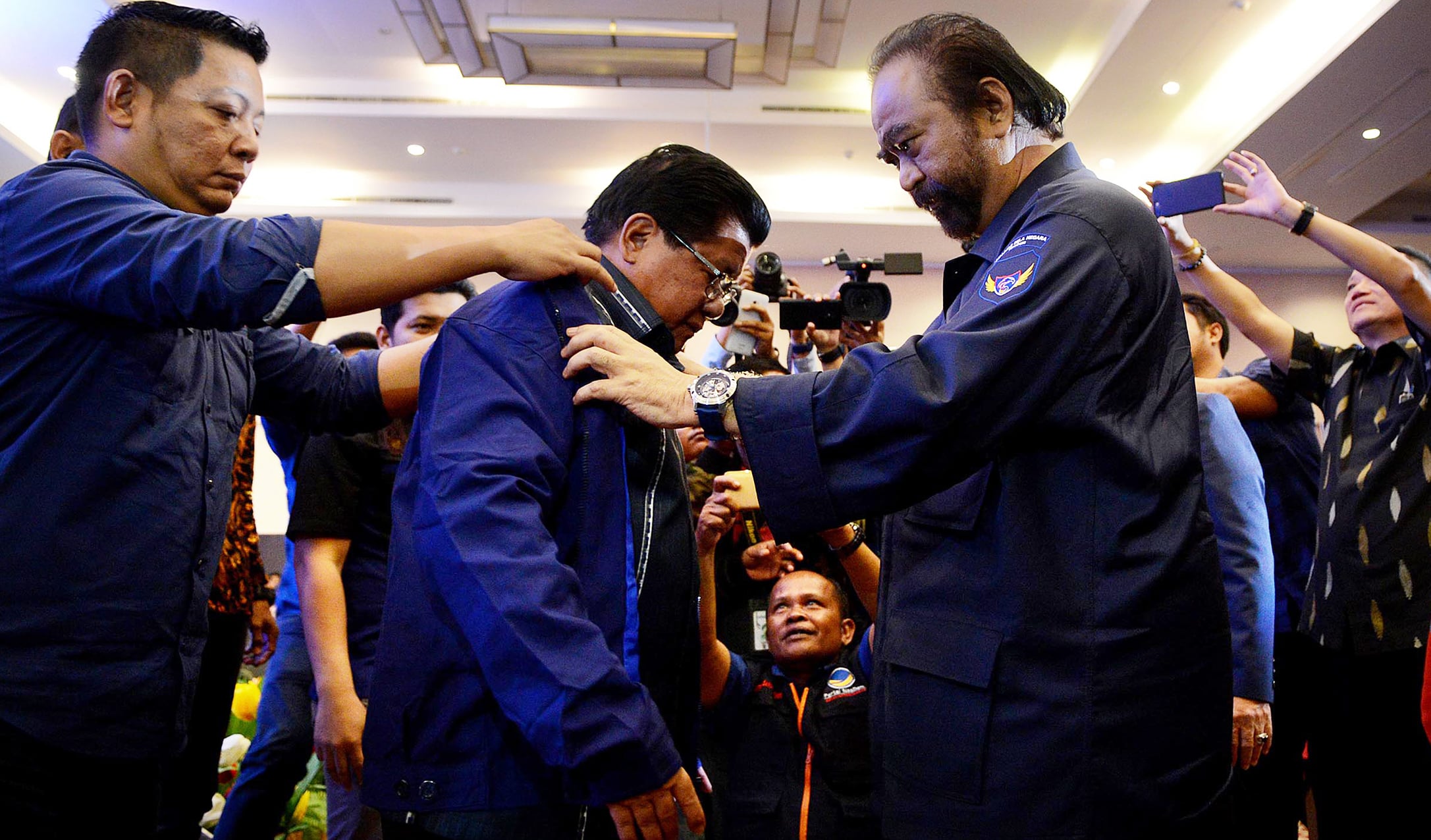 Ketua Umum Partai NasDem Surya Paloh (kedua kanan) mengenakan jaket partai kepada Mantan Gubernur Sulawesi Barat Anwar Adnan Saleh