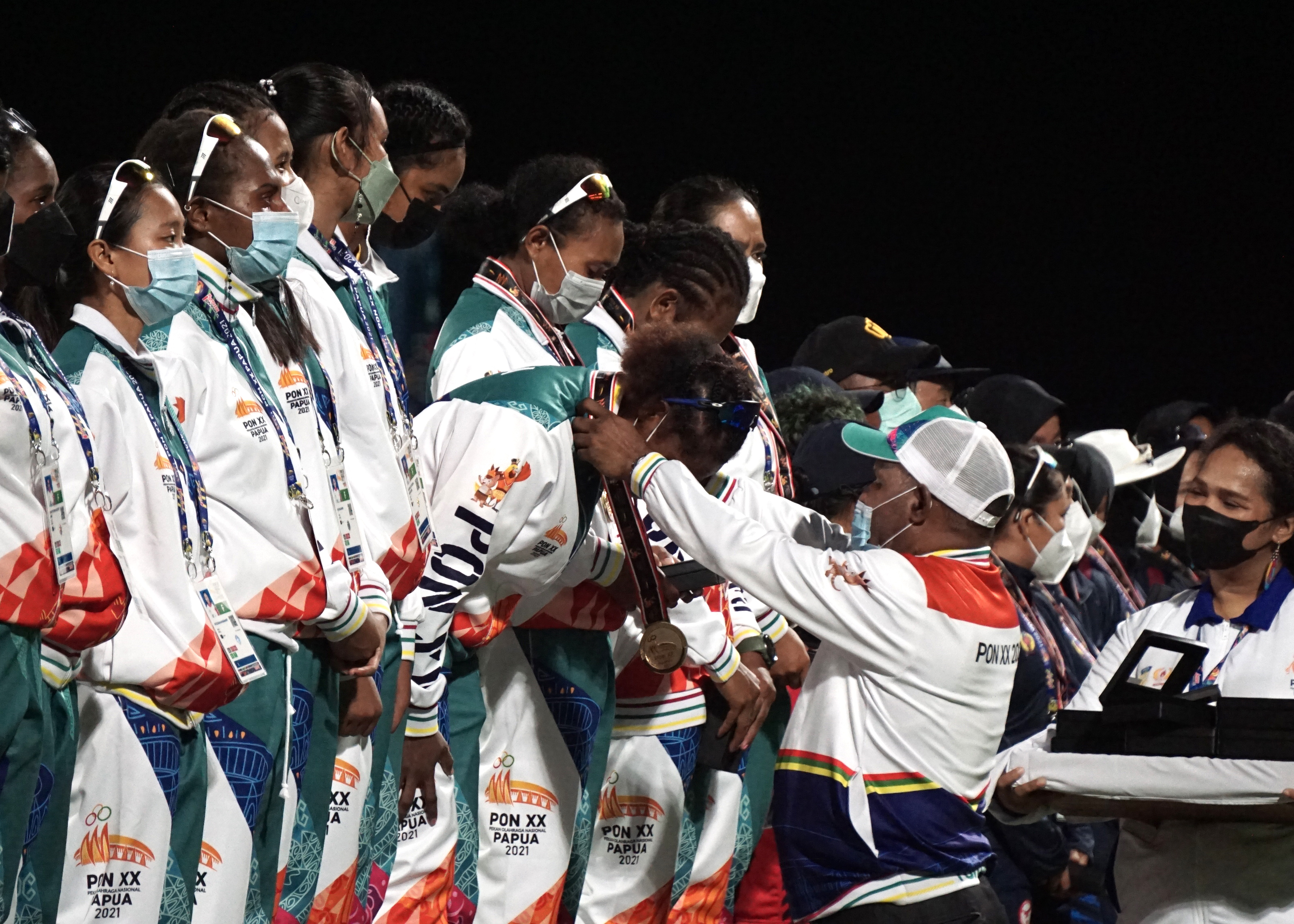 Ketua Harian PB PON mengalungkan medali emas ke tim kriket putri Papua.