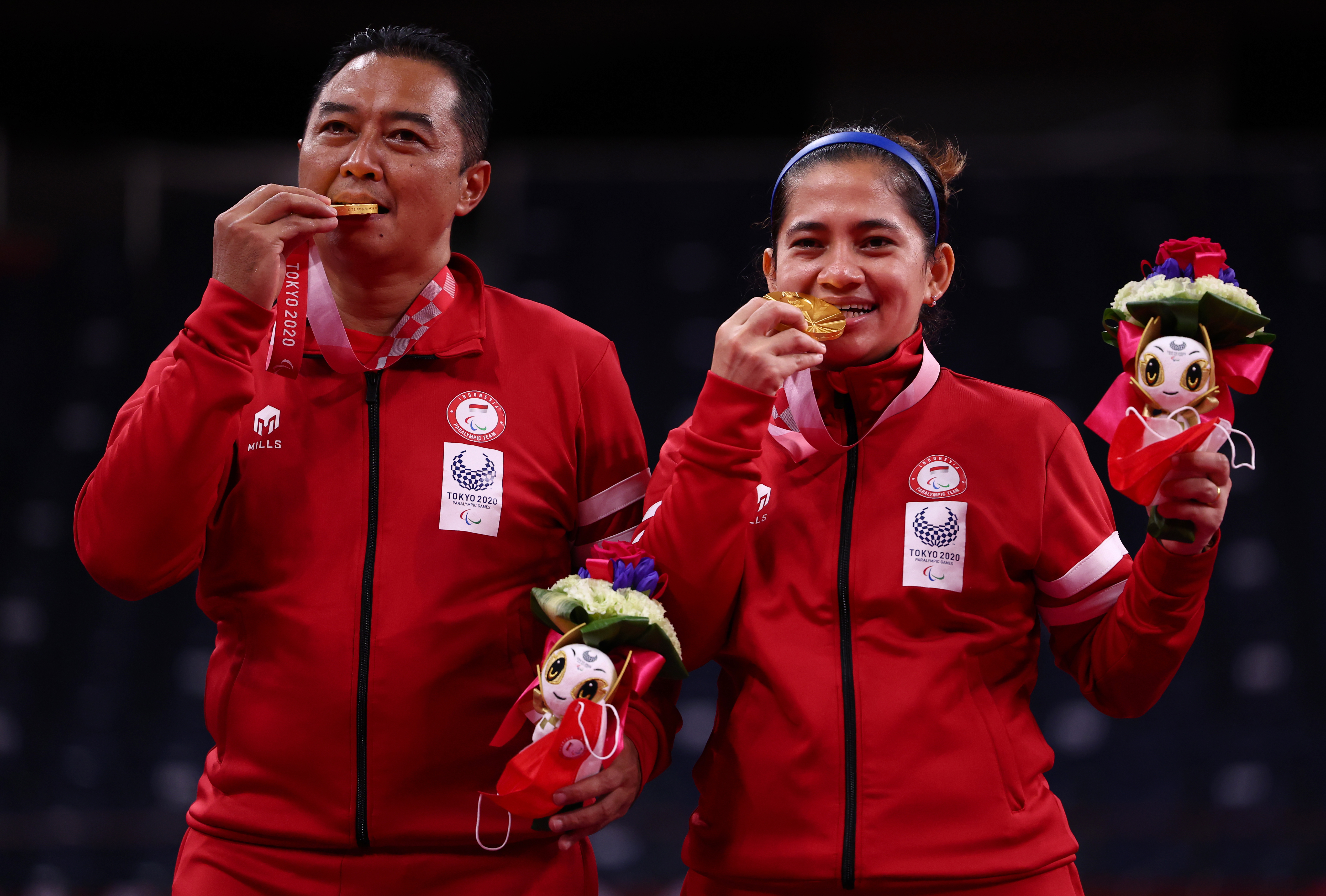 Atlet para-badminton indonesia Hary Susanto bersama Leani Ratri Oktila berpose dengan medali emas.