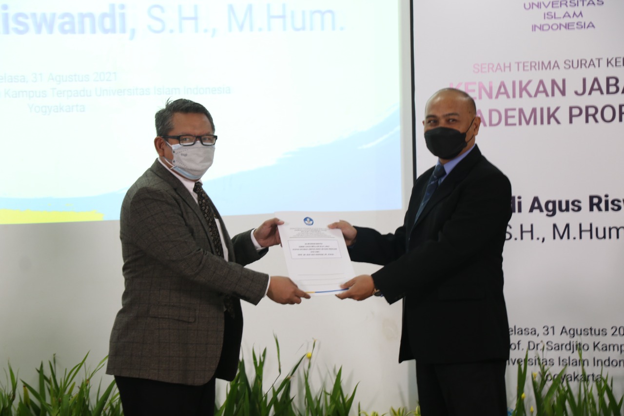  Rektor UII Prof. Fathul Wahid (masker putih) menyerahkan SK Guru Besar kepada guru besar baru UII, Budi Agus Riswandi, Selasa (31/8)