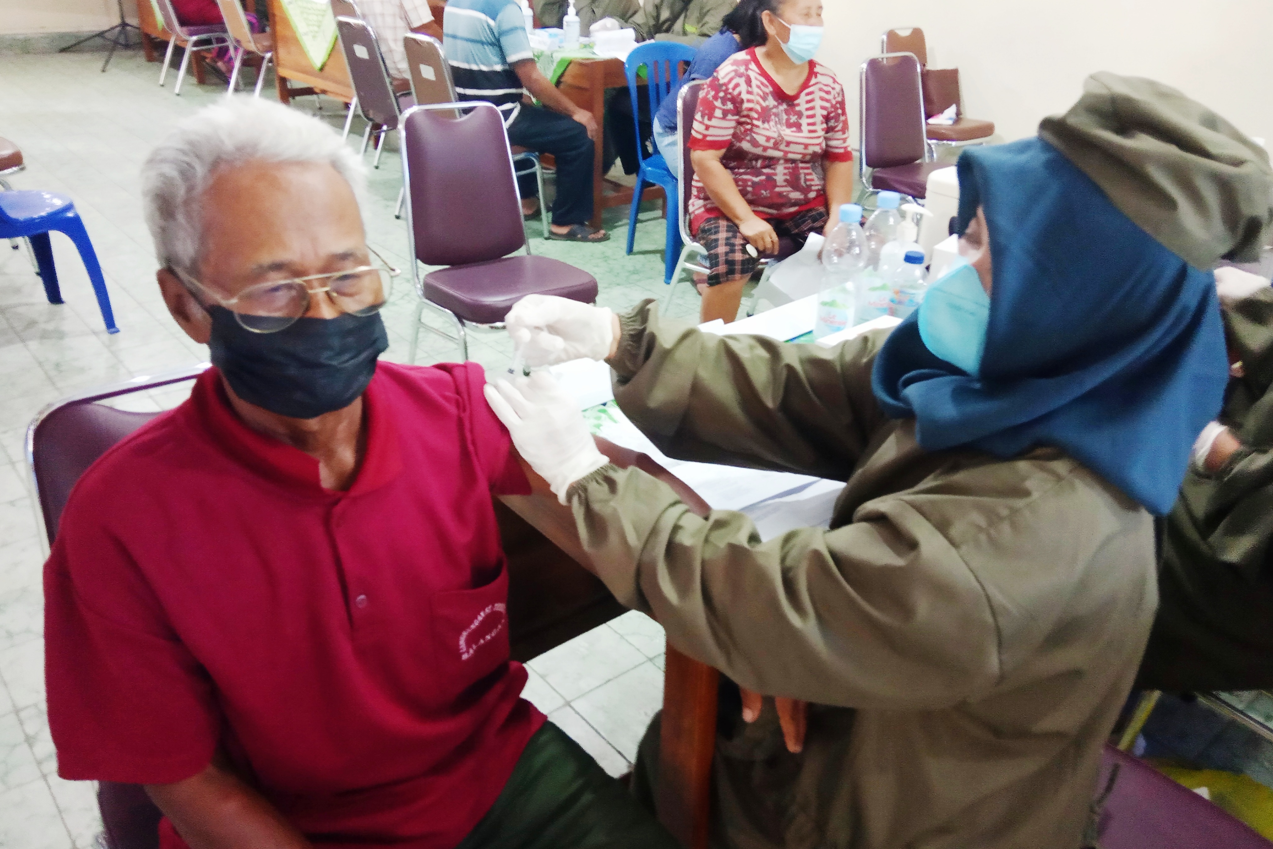 Salah seorang warga saat disuntik vaksin covid-19 oleh vaksinator. 