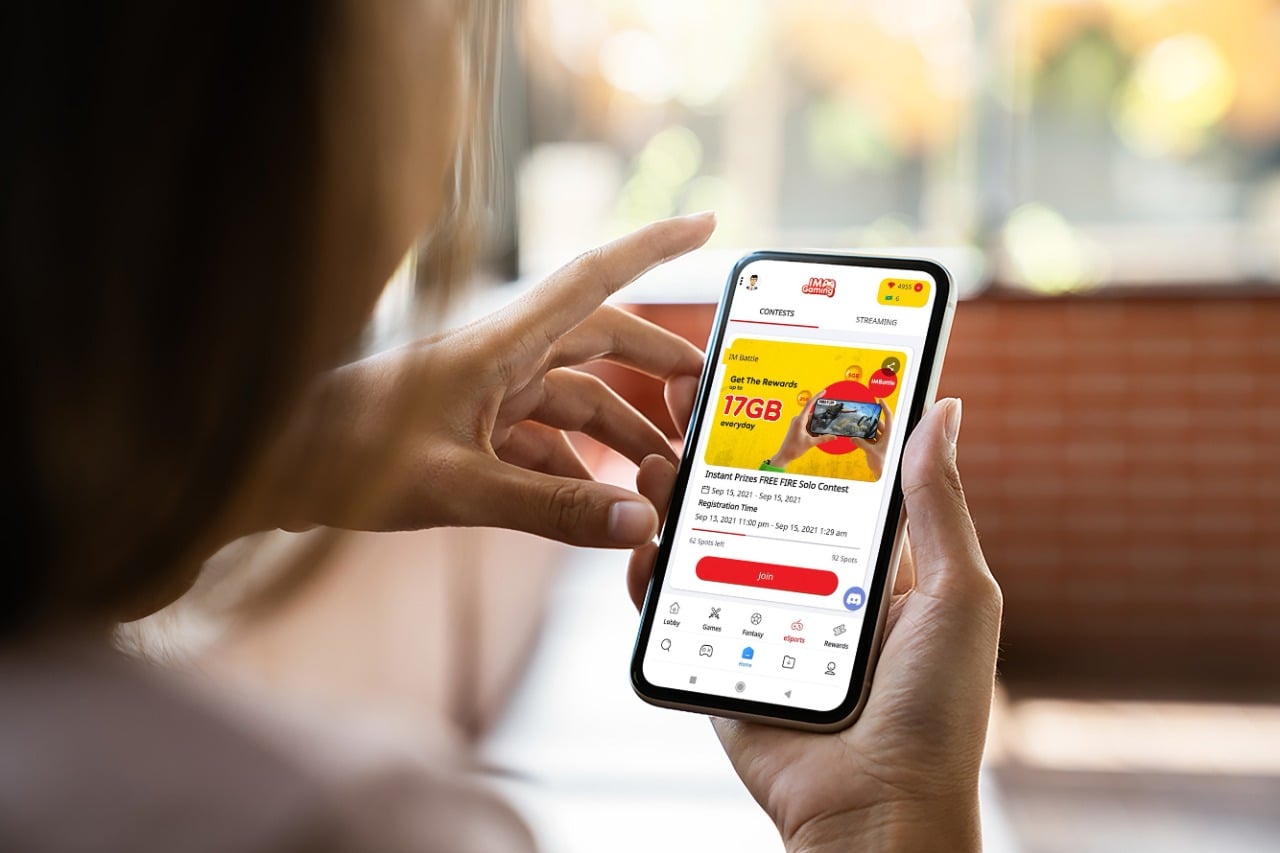 Seorang pengguna melihat aplikasi IMGaming di ponselnya.